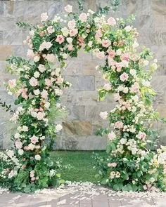 Outdoor flower arch made of blush flowers andd white roses with green foliage, set against a stone wall at a Simcoe-Muskoka wedding venue. 