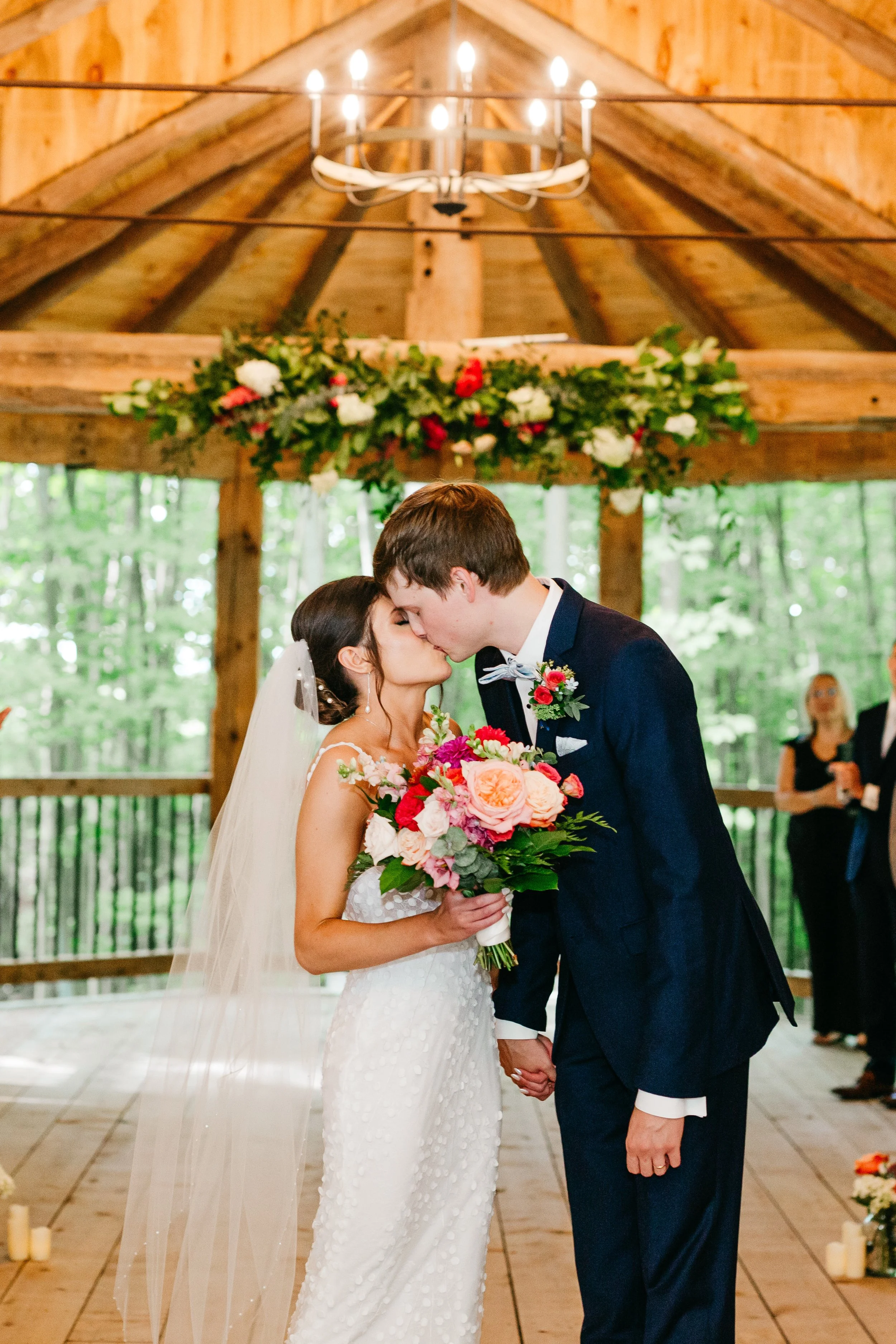 A bride and groom sharing a kiss during their wedding ceremony at Ivy Ridge  historical barn venue decorated with flowers and candles.