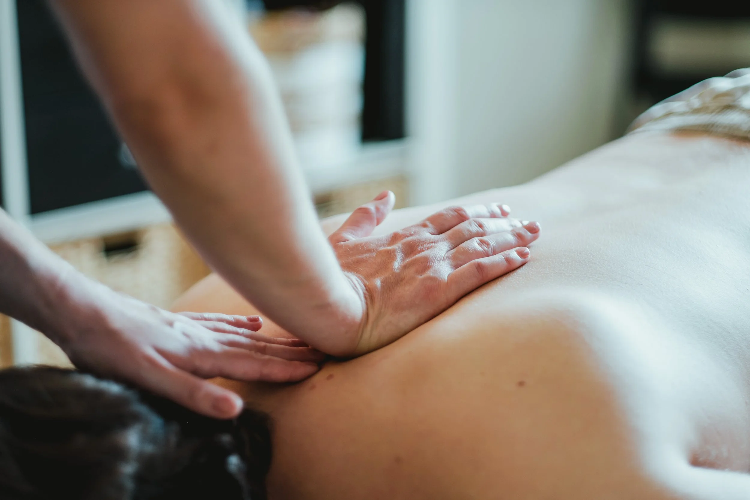 Une personne fait un massage sur le dos d'une autre personne dans un environnement intérieur.