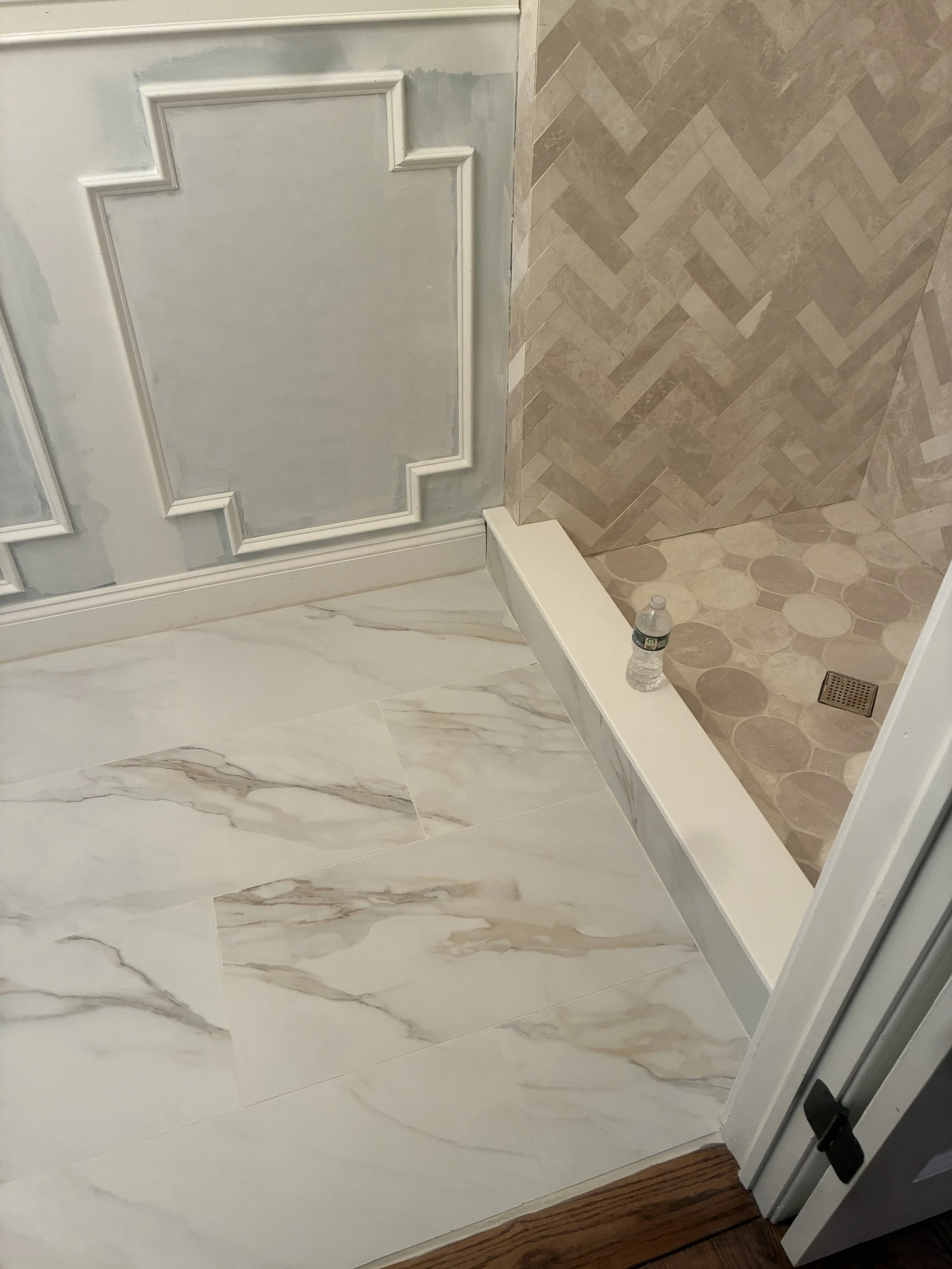 New shower build with herringbone layout, custom wainscoating, 12"x24" floor tile and new curb.
