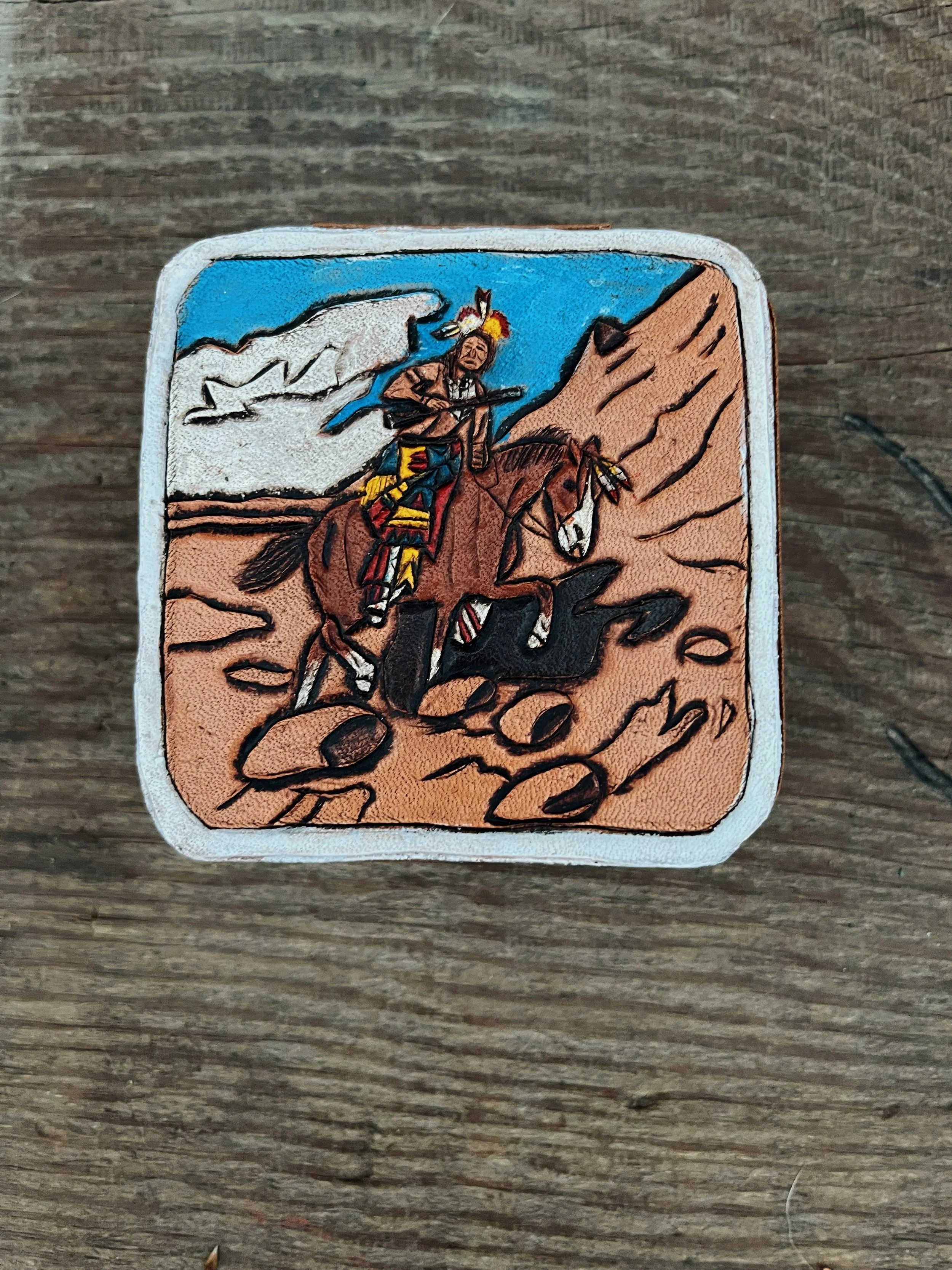 Patch featuring Native American man riding a horse, holding a spear, with mountains and a blue sky in the background.