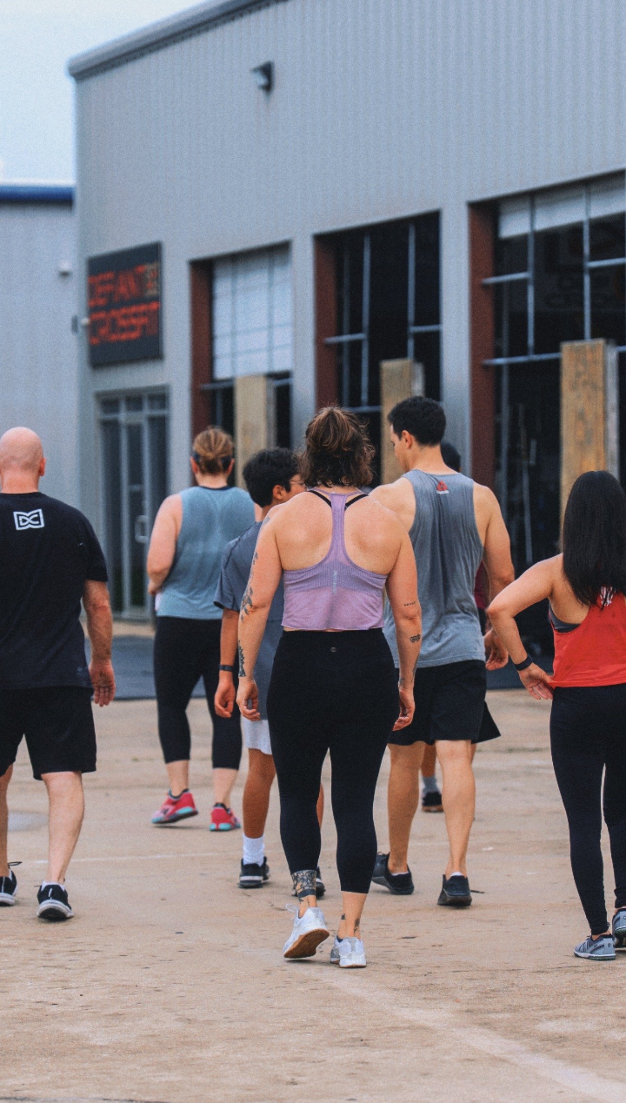 Group of people walking together outside, some wearing athletic clothing.