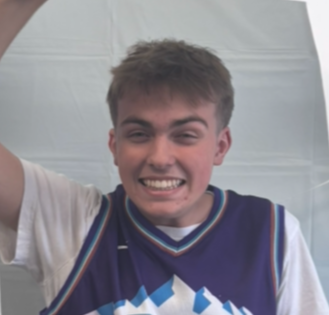 Young man smiling and raising his arm, wearing a sports jersey.