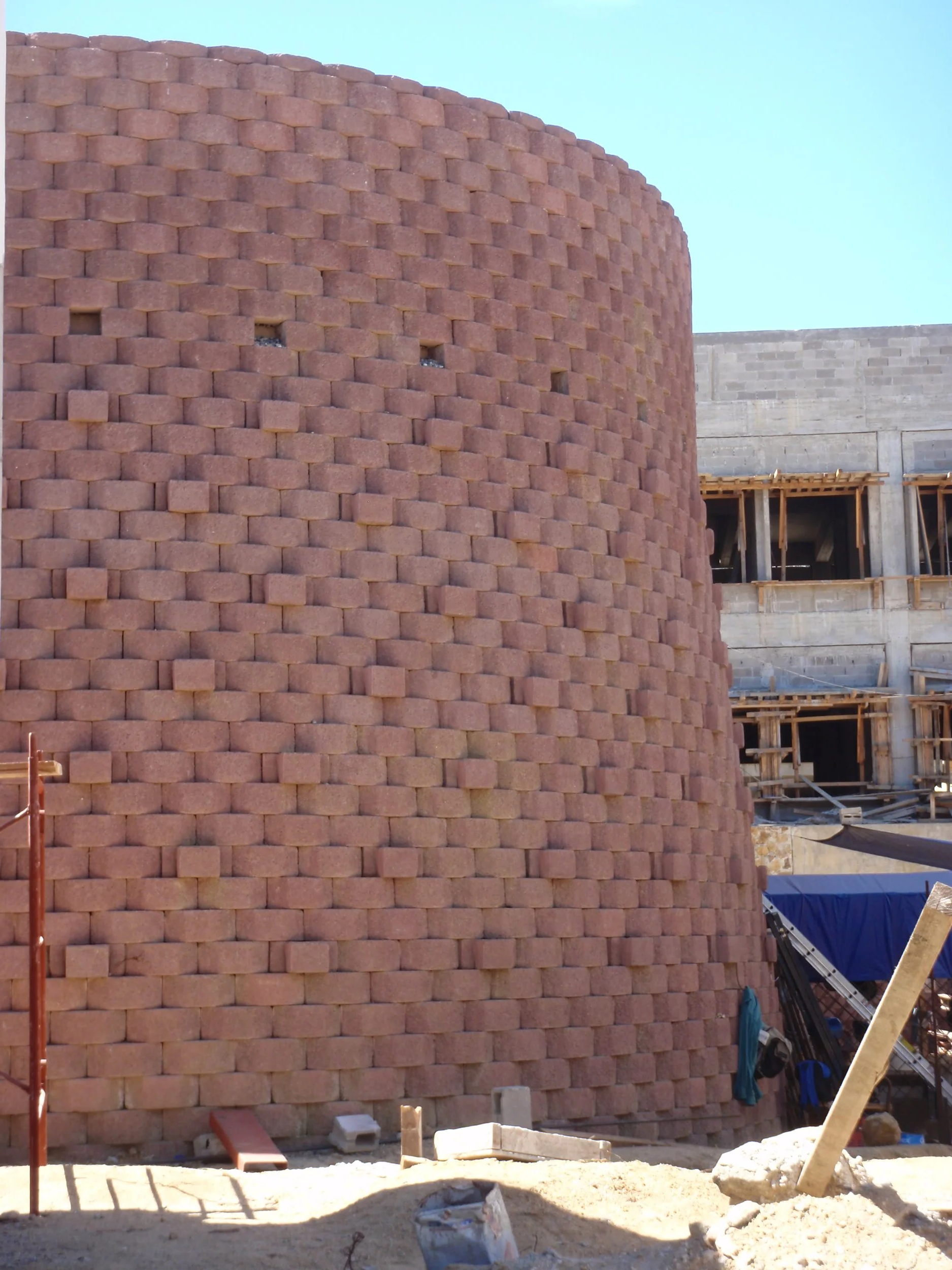 Muro de ladrillos en construcción con estructura de cemento en el fondo.