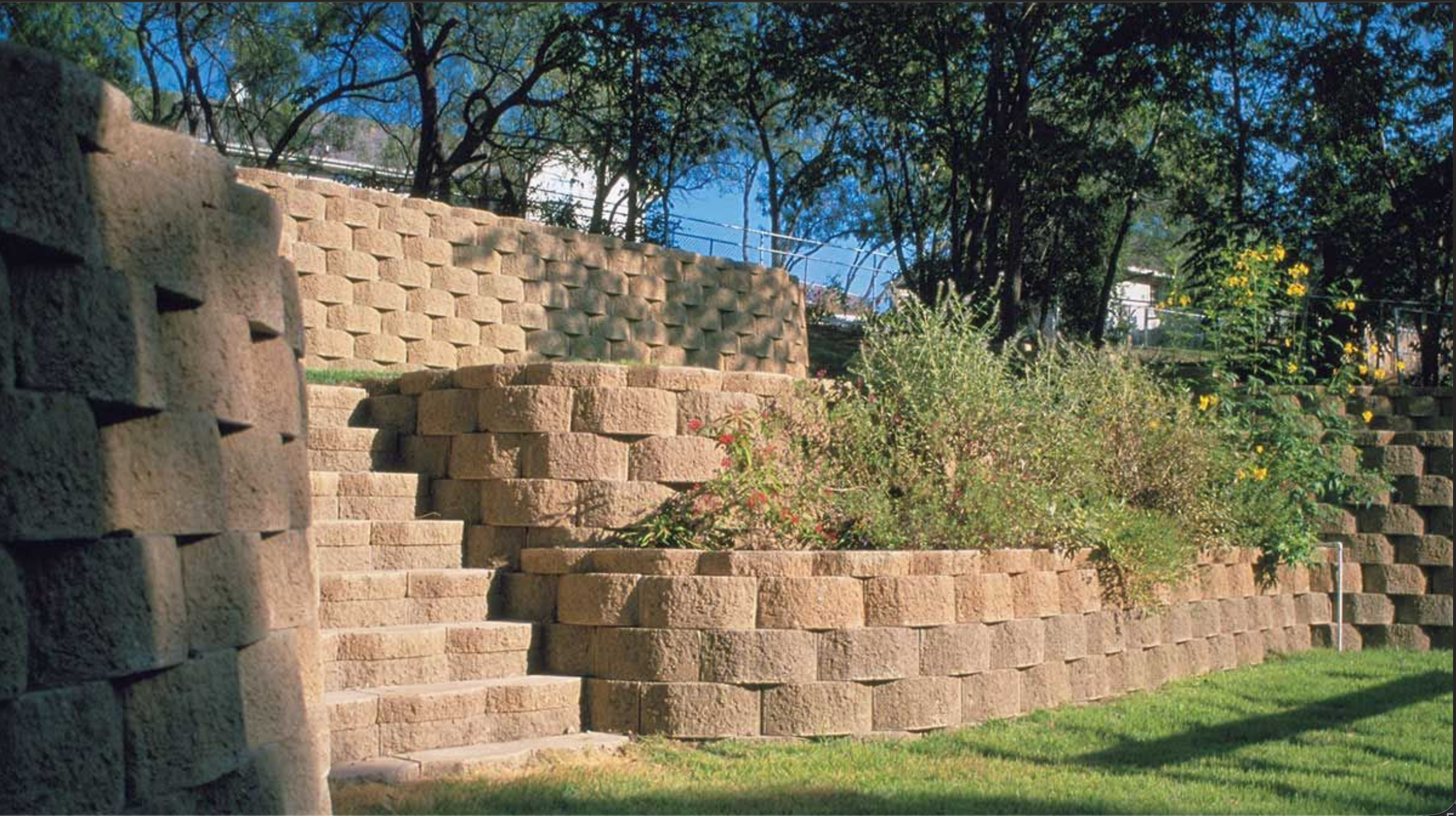 Escalera de bloques de piedra con plantas y árboles en un entorno al aire libre.