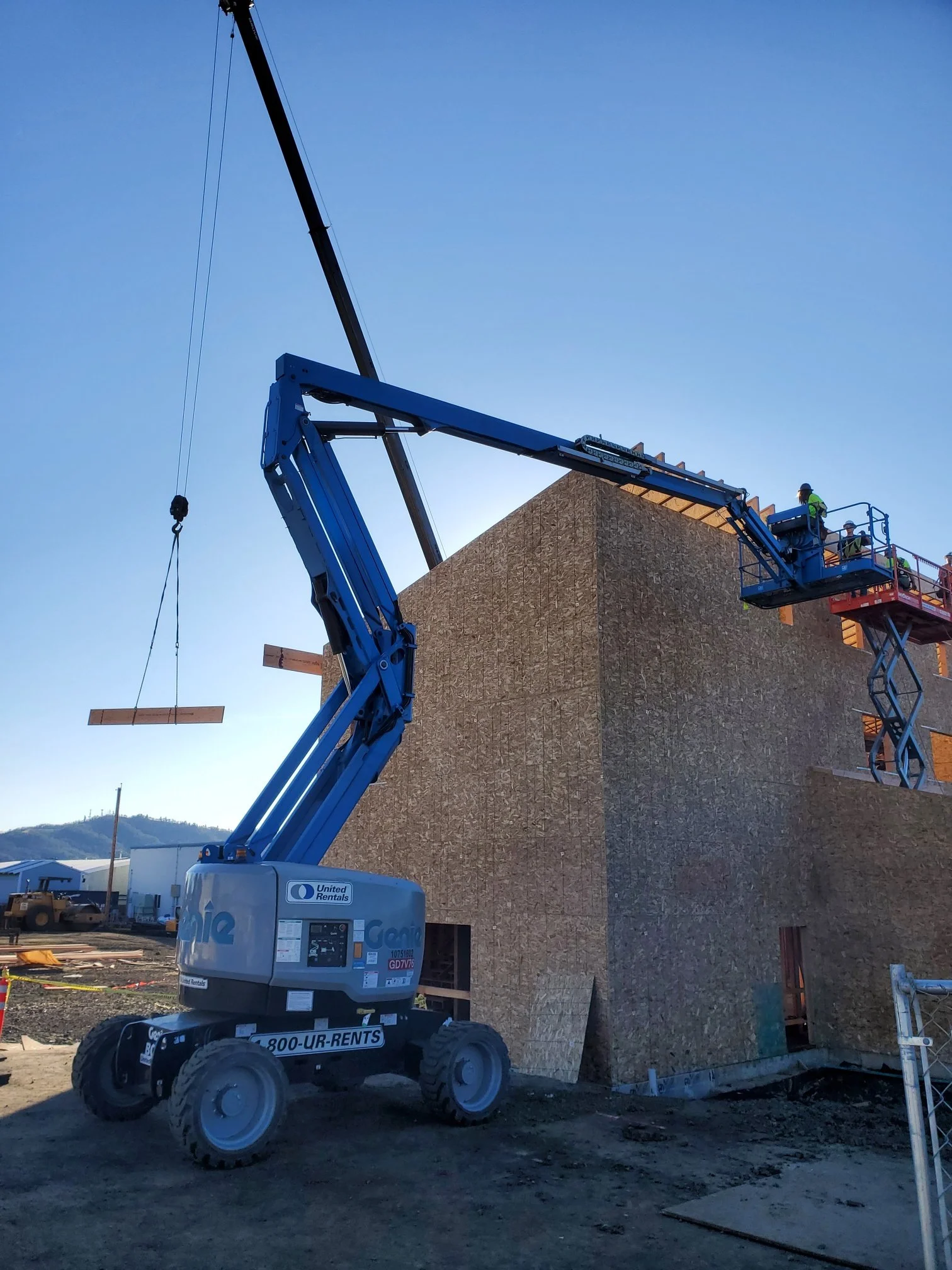 Construction crew installing structural framing on a multi-story commercial building using crane and lift equipment.jpg