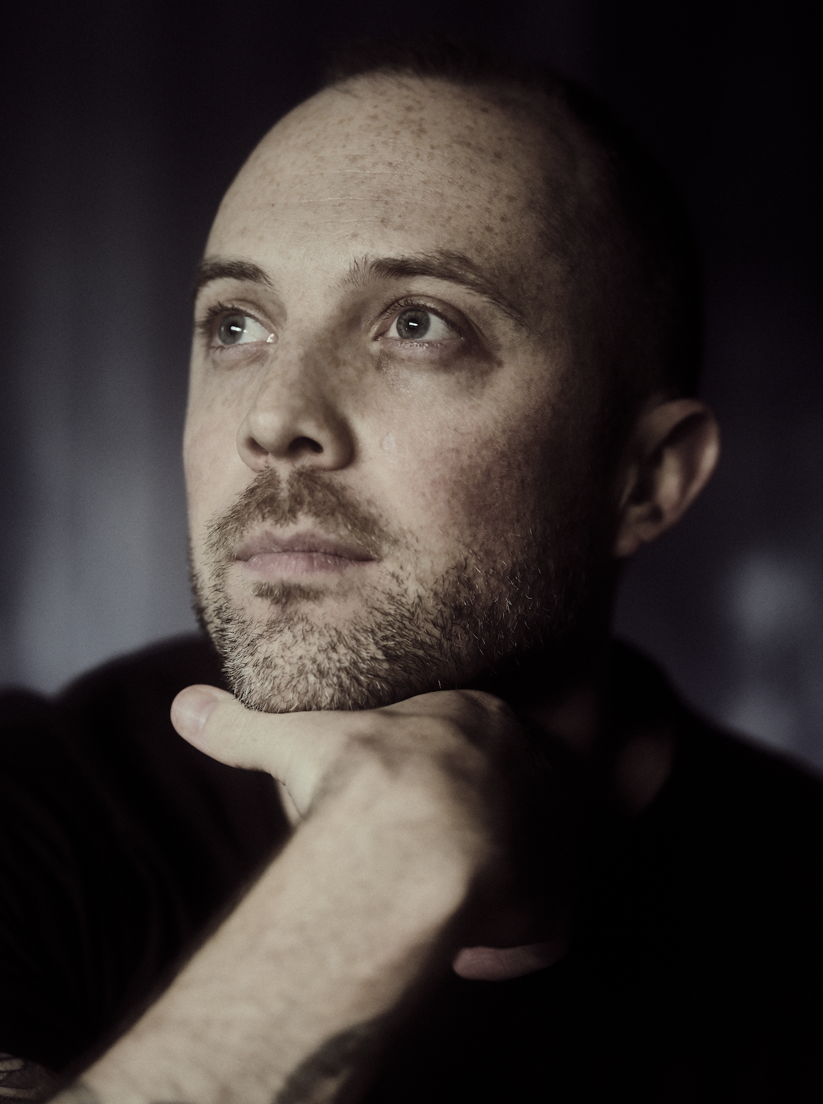 Portrait of Brandon Sieve looking upward with his hand resting on his chin.