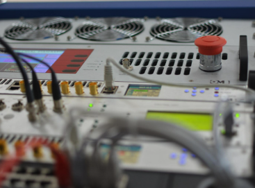 Close-up of electronic equipment with various knobs, buttons, and a red emergency stop button, possibly a control panel or sound mixer.