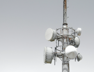 Cell tower with multiple antenna dishes and equipment mounted on it.