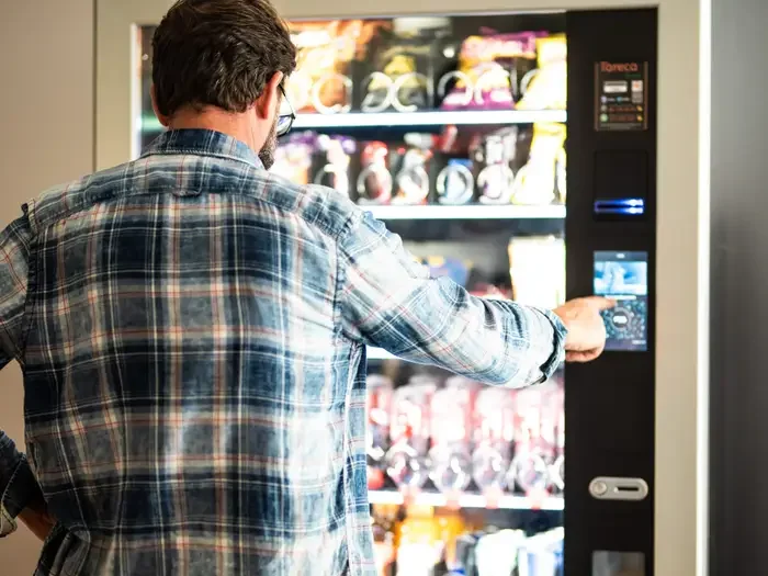 A man in a plaid shirt using a vending machine.