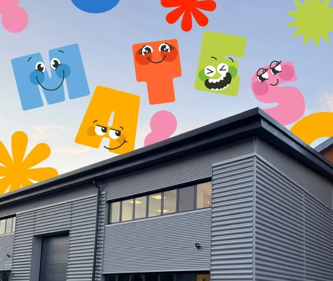 Colorful animated numbers with smiling faces are floating above a gray industrial building with a metal exterior and windows.