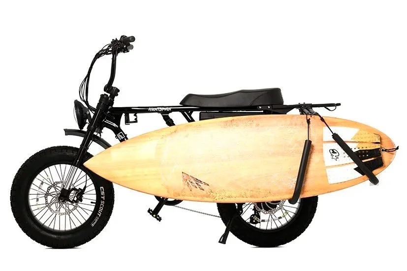 Electric bicycle with a surfboard mounted on its side.