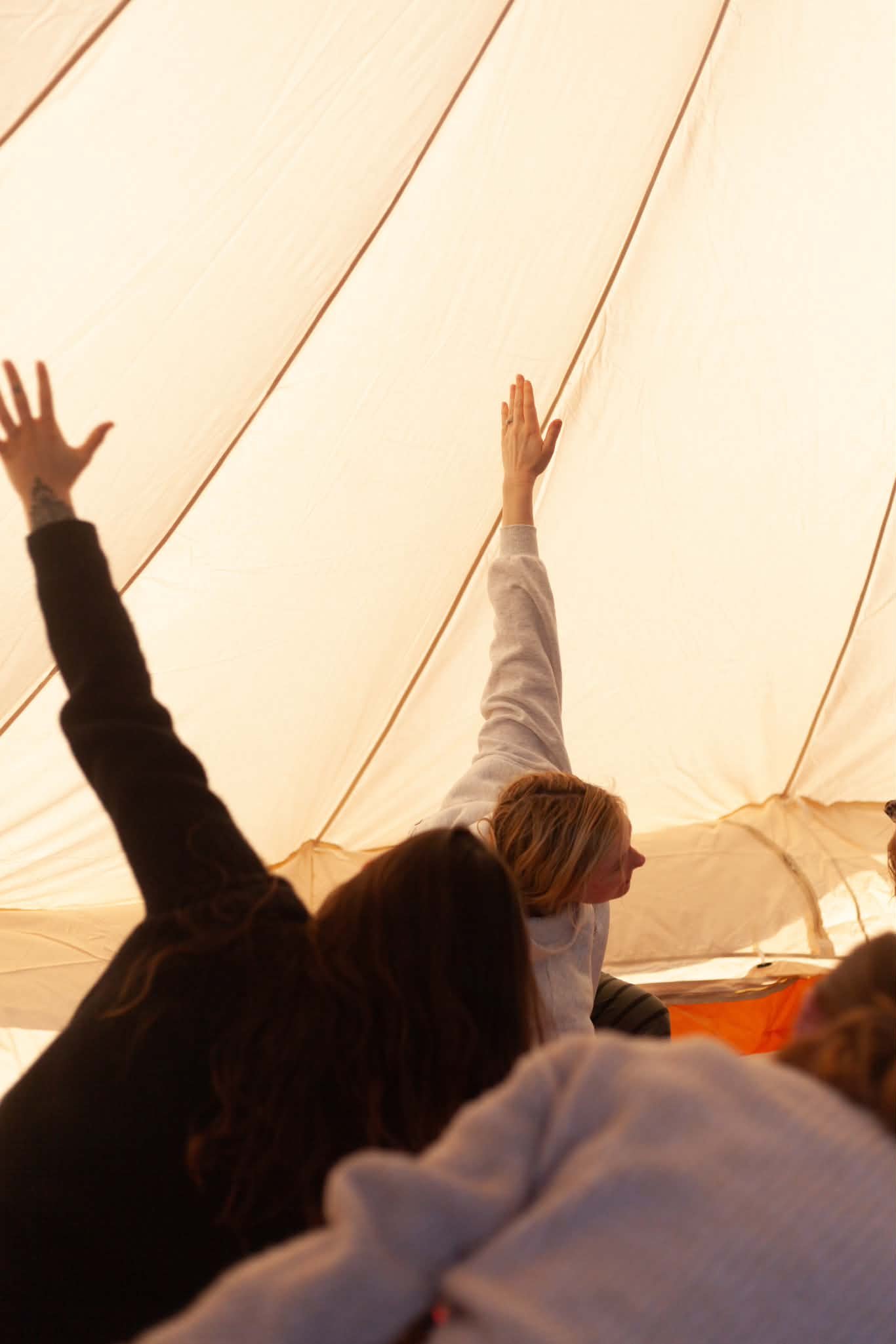 People inside a tent reaching up to touch the fabric ceiling.