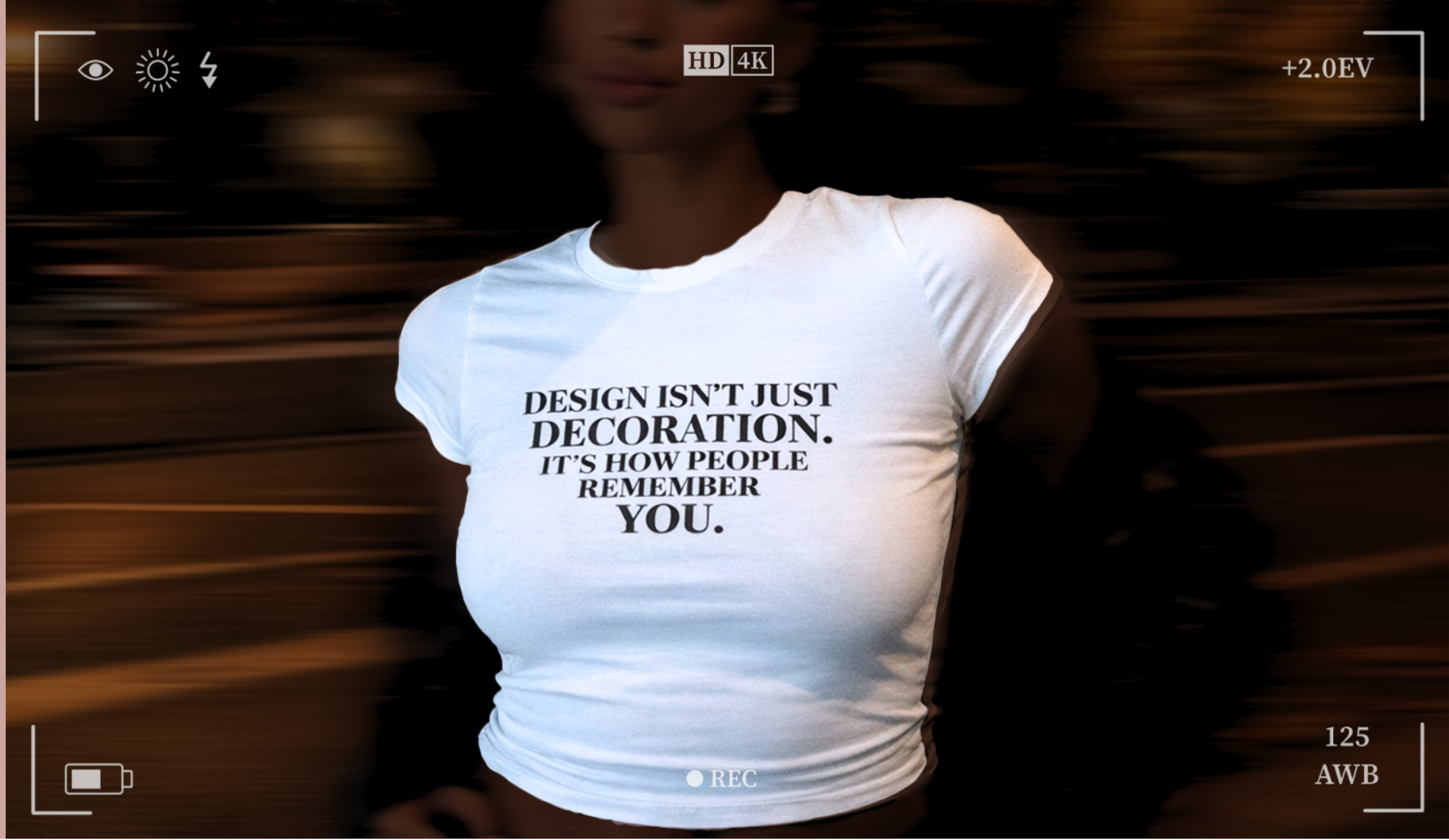 Person wearing a white T-shirt with black text that reads, 'Design isn’t just decoration. It’s how people remember you.'