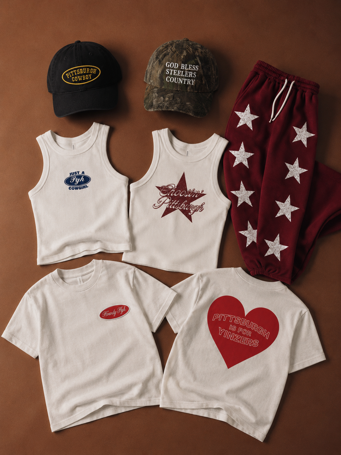 Collection of Pittsburgh-themed clothing and accessories including two baseball caps, two white tank tops, and two white T-shirts with Pittsburgh-related phrases and symbols. The baseball caps bear Pittsburgh-related messages, one with camouflage des