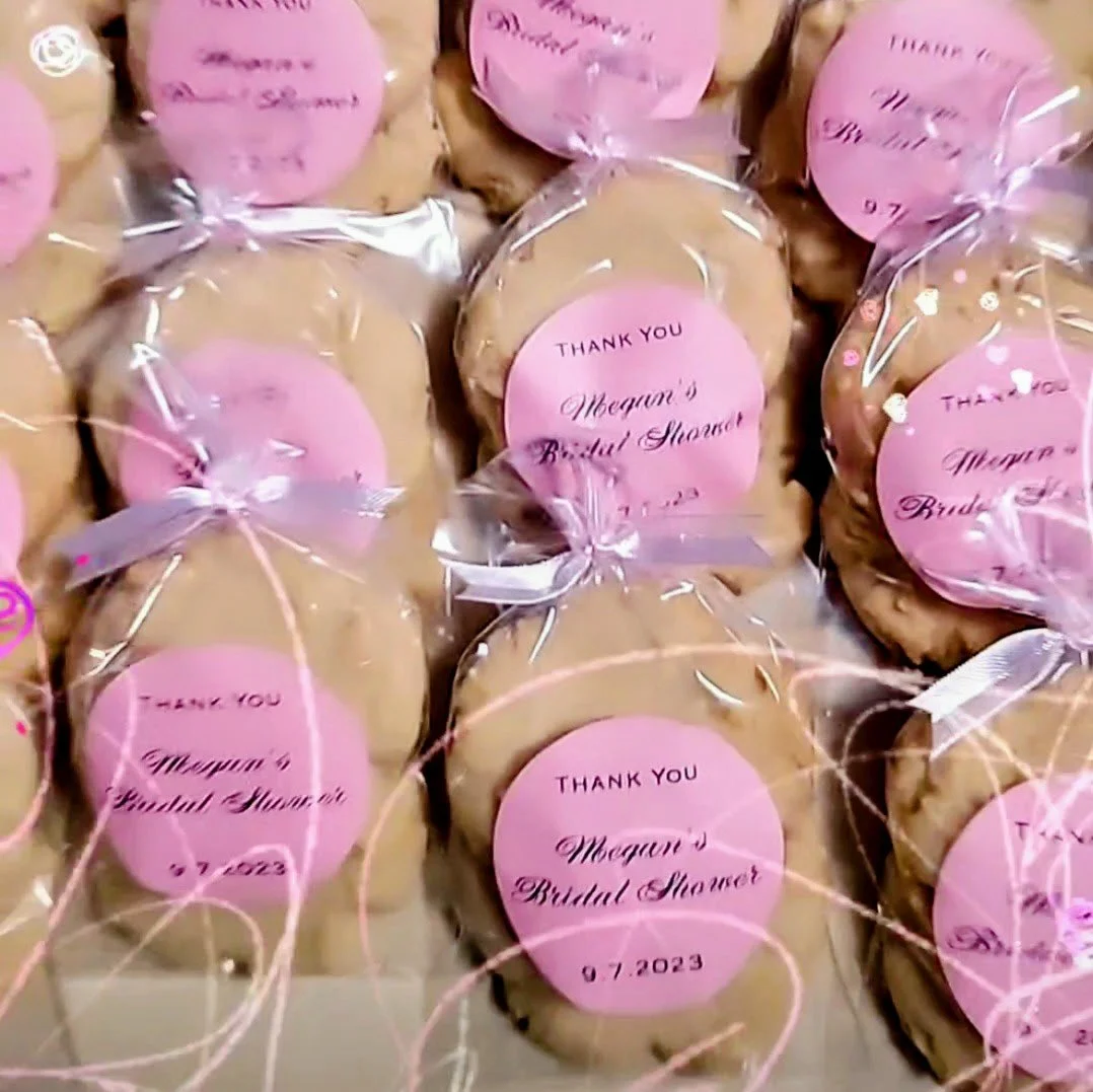 Cookies wrapped in clear plastic with pink circular labels that say "Thank You Megan's Bridal Shower 07.2023."