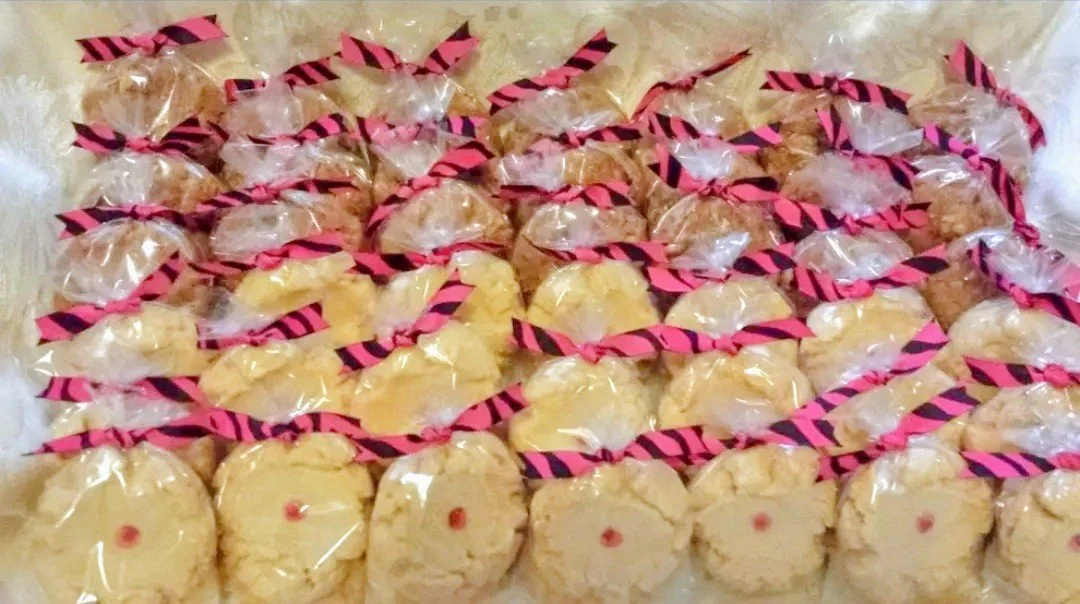 Multiple wrapped cookies with pink and black striped twist ties, arranged closely on a surface.