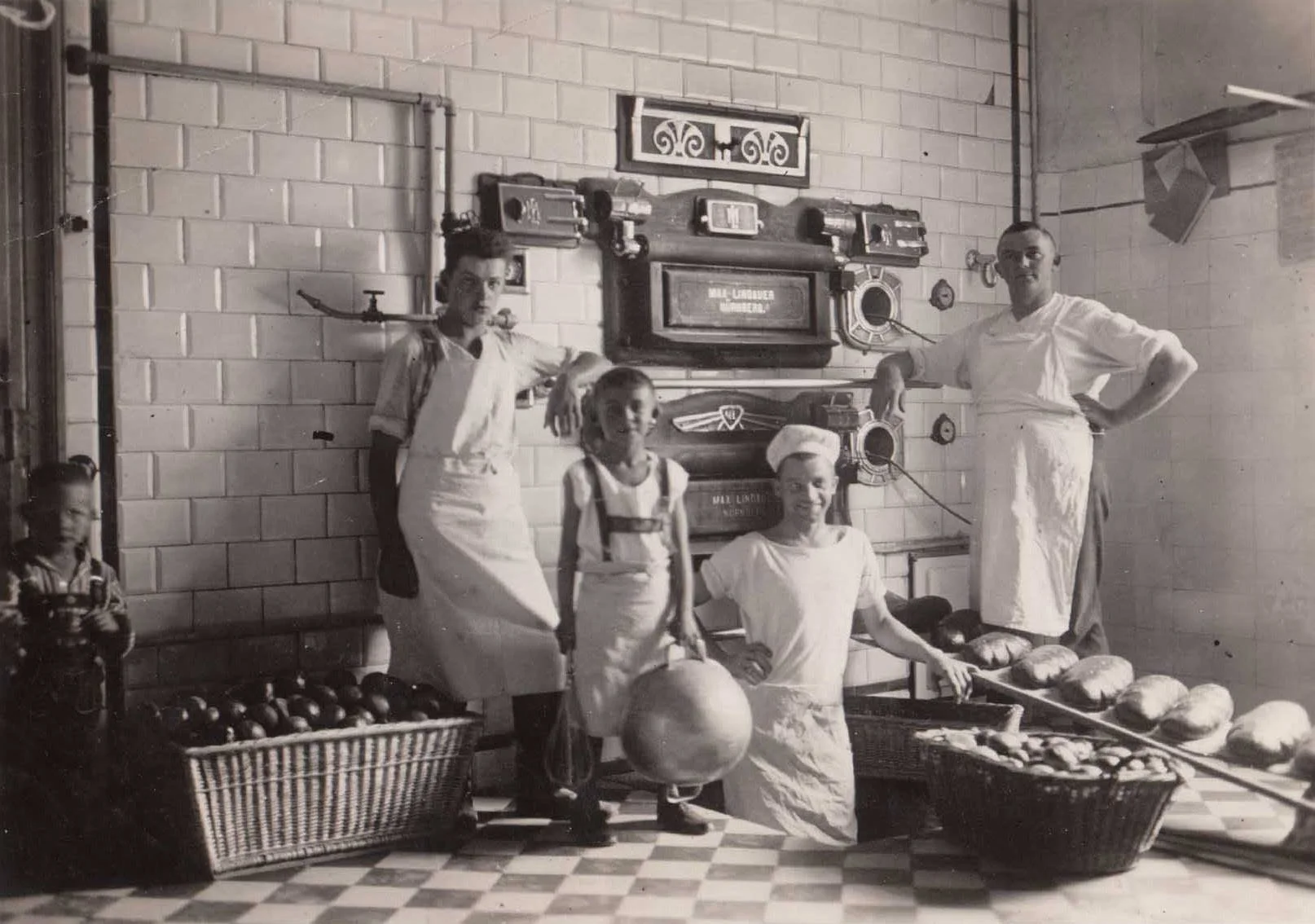 Schwarz-weiß-Foto von fünf Menschen, darunter Kinder, in einem Laden mit verschiedenen Obst- und Gemüsesorten, und einer Wand mit alten Radios im Hintergrund.