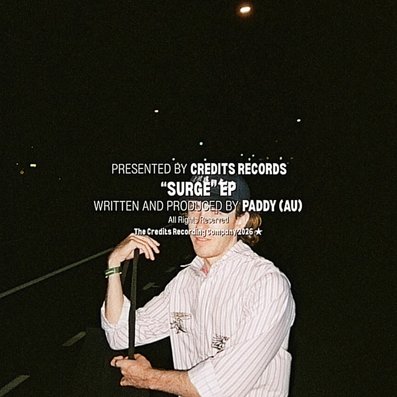 Text overlay on a dark background reads: 'Presented by Credits Records Surge EP written and produced by Paddy (AU) All Rights Reserved The Credits Recording Company 2026'. Behind the text, a woman in a striped shirt holding an umbrella is partially visible, with a dark night sky above.