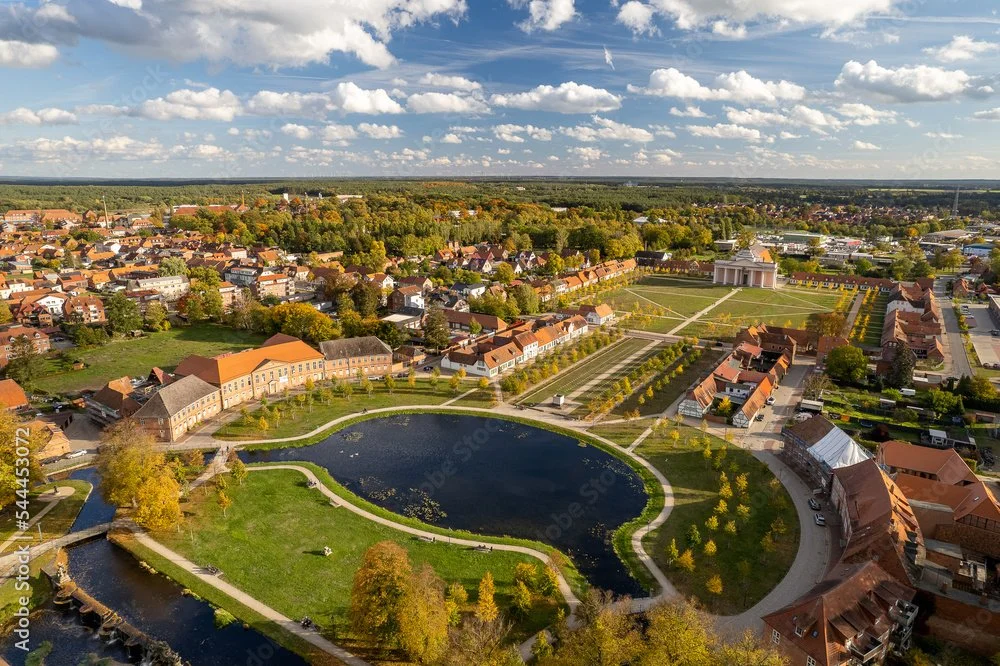 Luftaufnahme einer Stadt mit Park, Wasser, Häusern und Straßen bei bewölktem Himmel