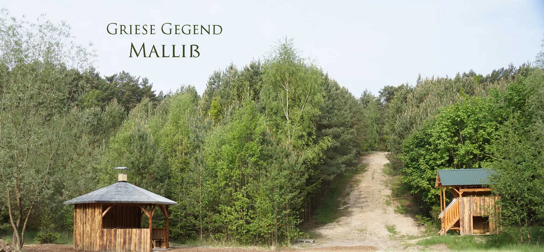 Ein Waldweg mit zwei kleinen Holzhütten, umgeben von grünen Bäumen und einem blauen Himmel, mit dem Schriftzug 'Griese Gegend Mallib'.