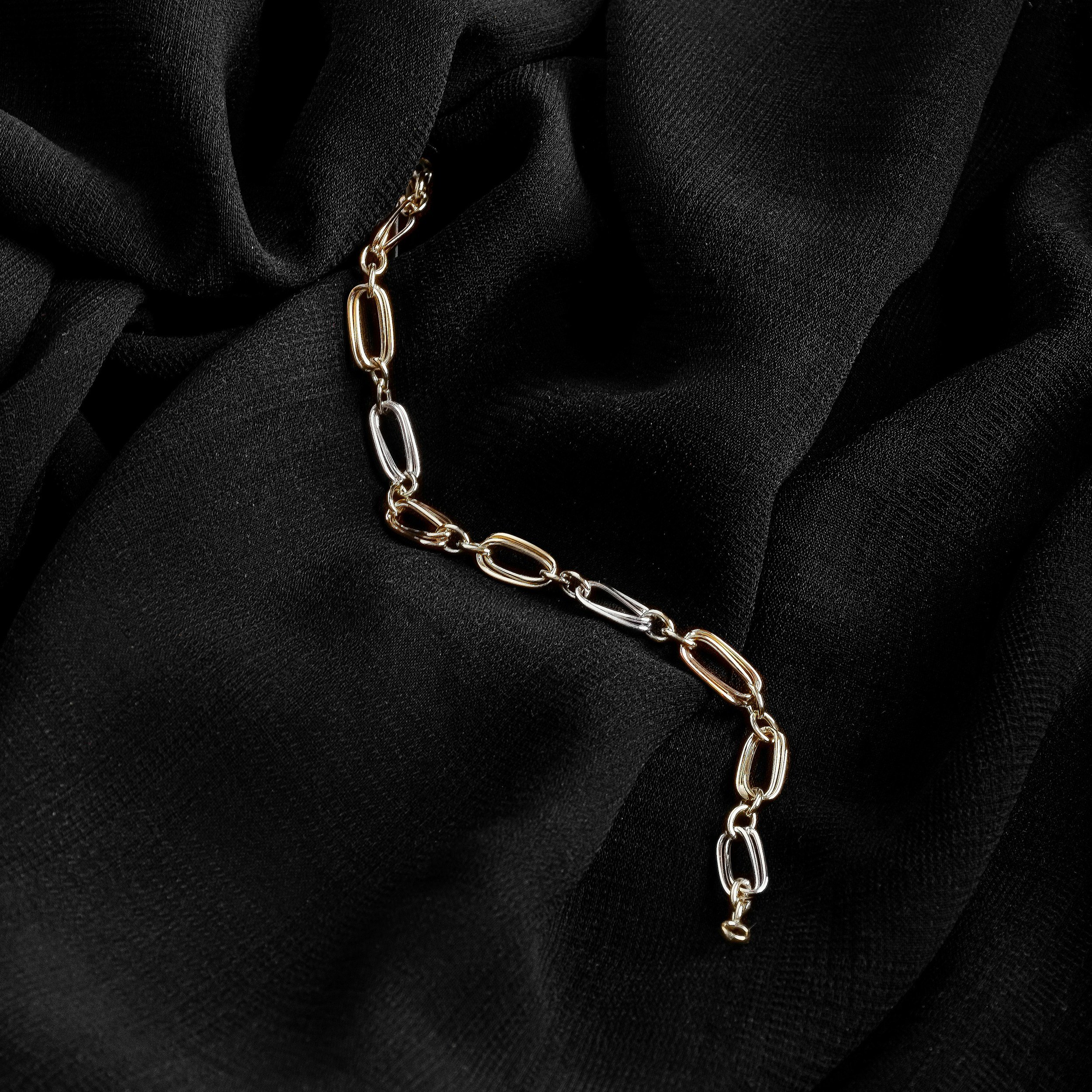 Close-up of a silver chain necklace on black fabric background.