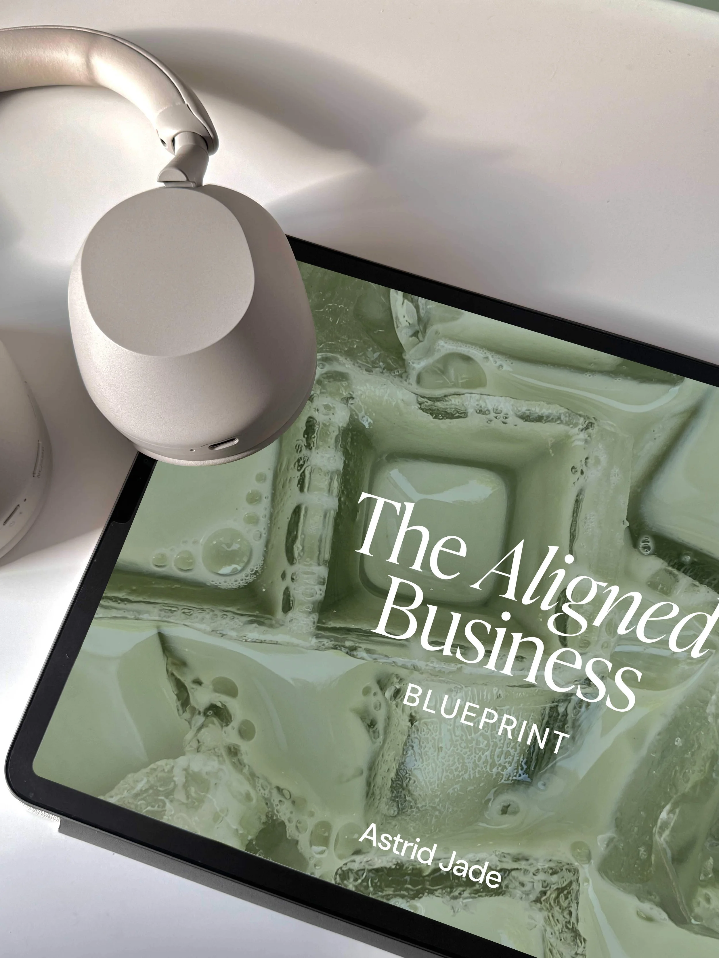 Schermo di un tablet con il titolo 'The Aligned Business' e sottotitolo 'BLUEPRINT' con sfondo di un liquido verde e bolle d'aria.