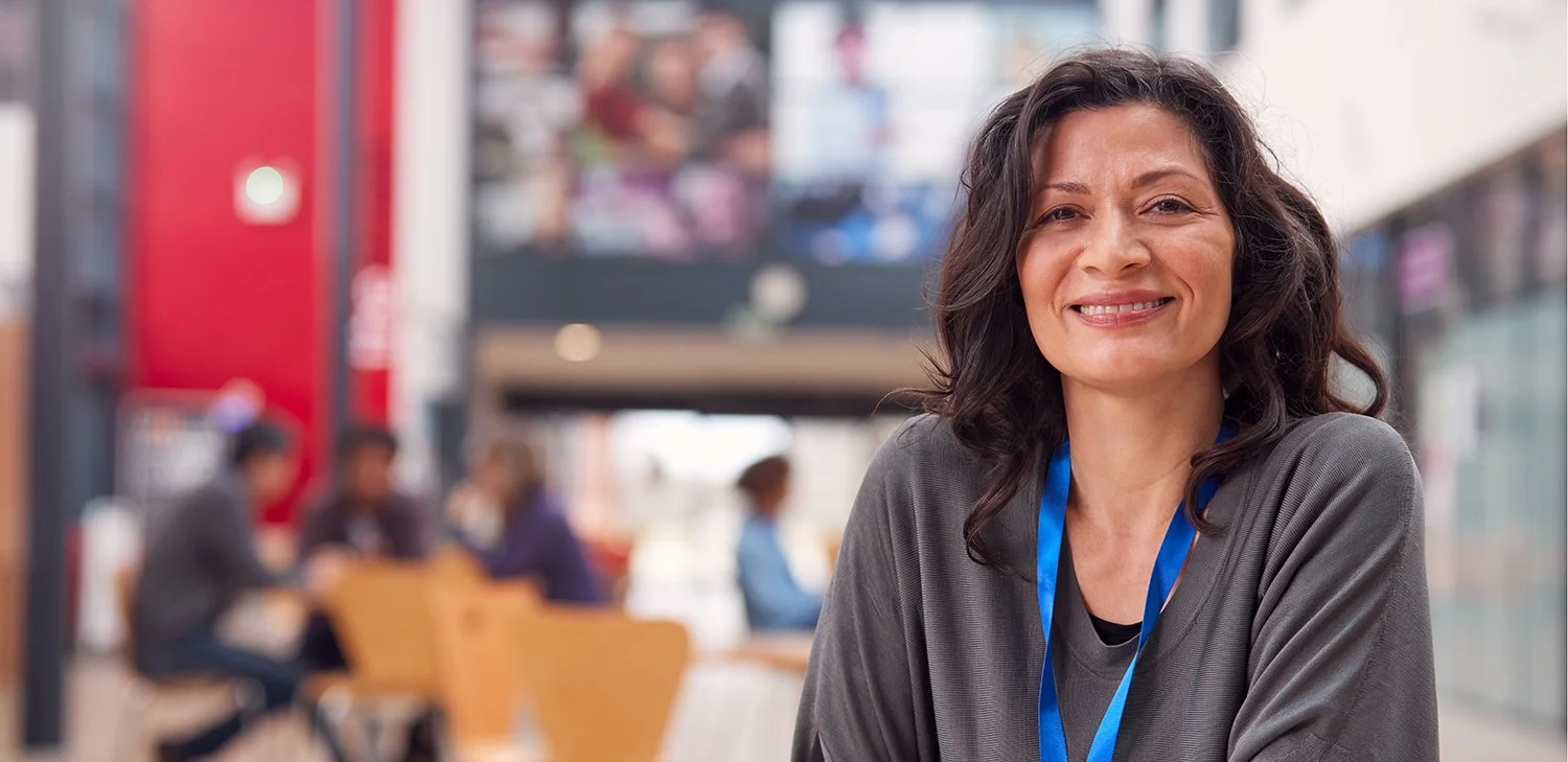 A teacher of Directions to Diploma smiling and sitting (hero image)