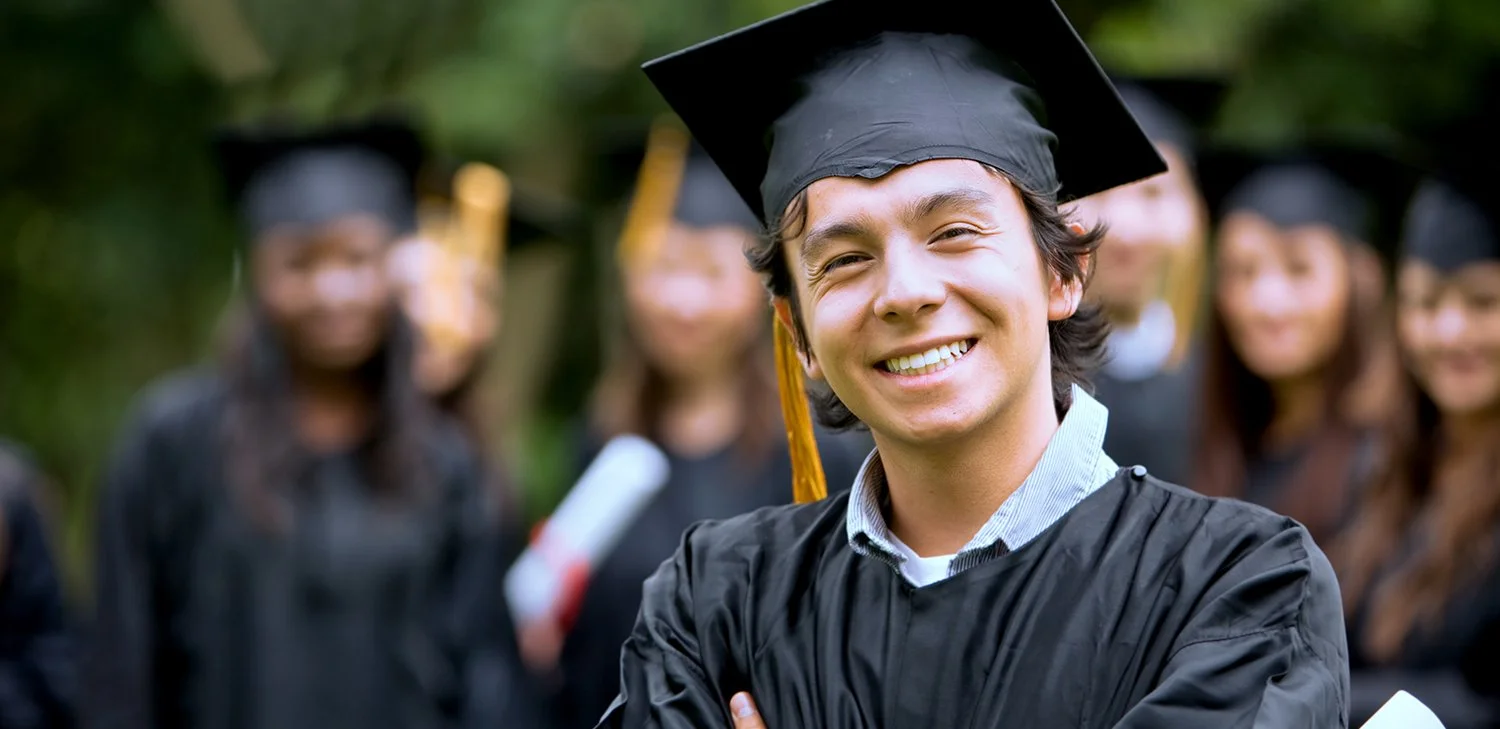 A male graduate of Directions to Diploma smiling and standing outside after the graduation ceremony (hero image)