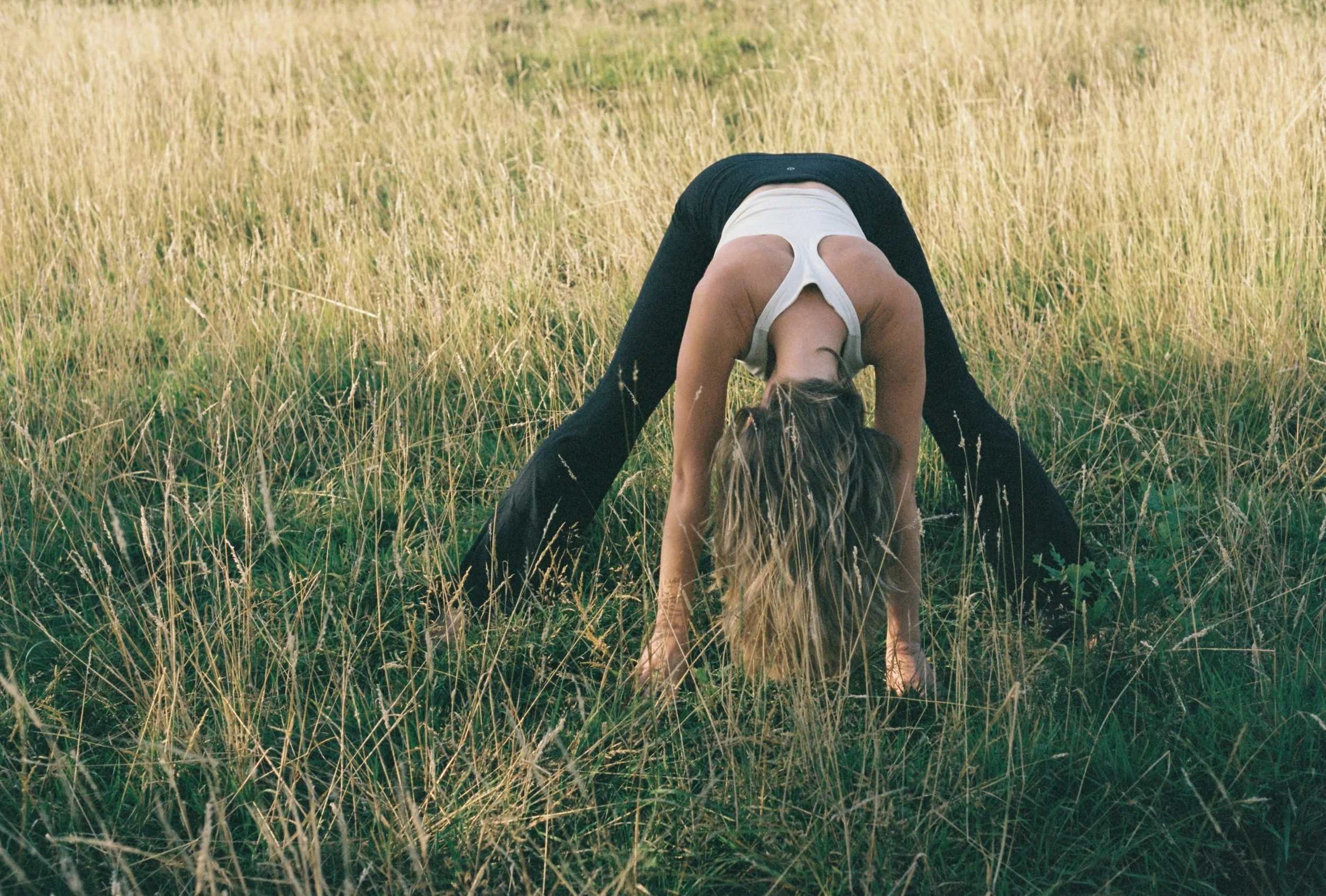 A person in yoga pose in a grassy field during daytime.