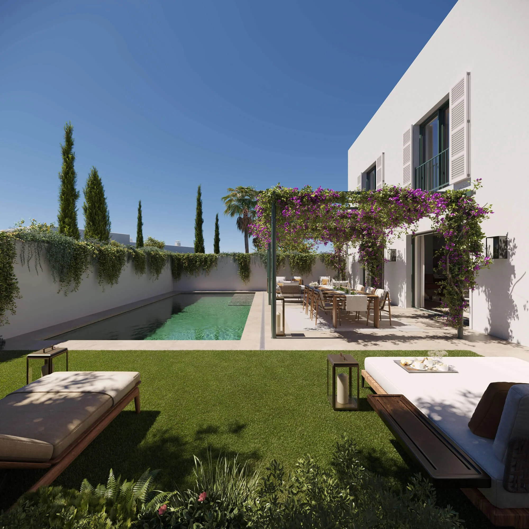 A modern white house with open windows and shutters, surrounded by trees and flowering plants, with an outdoor dining area and sun loungers in a backyard under a clear blue sky.