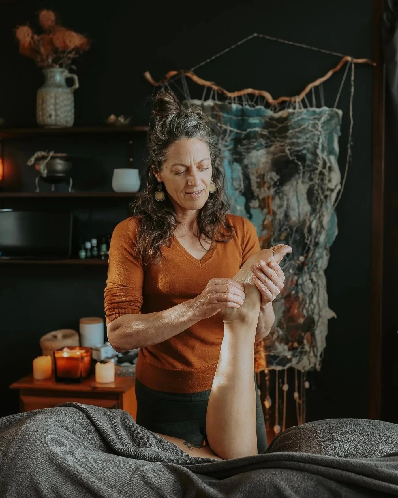 Gina is focussing on a clients foot while they lay on the massage table.