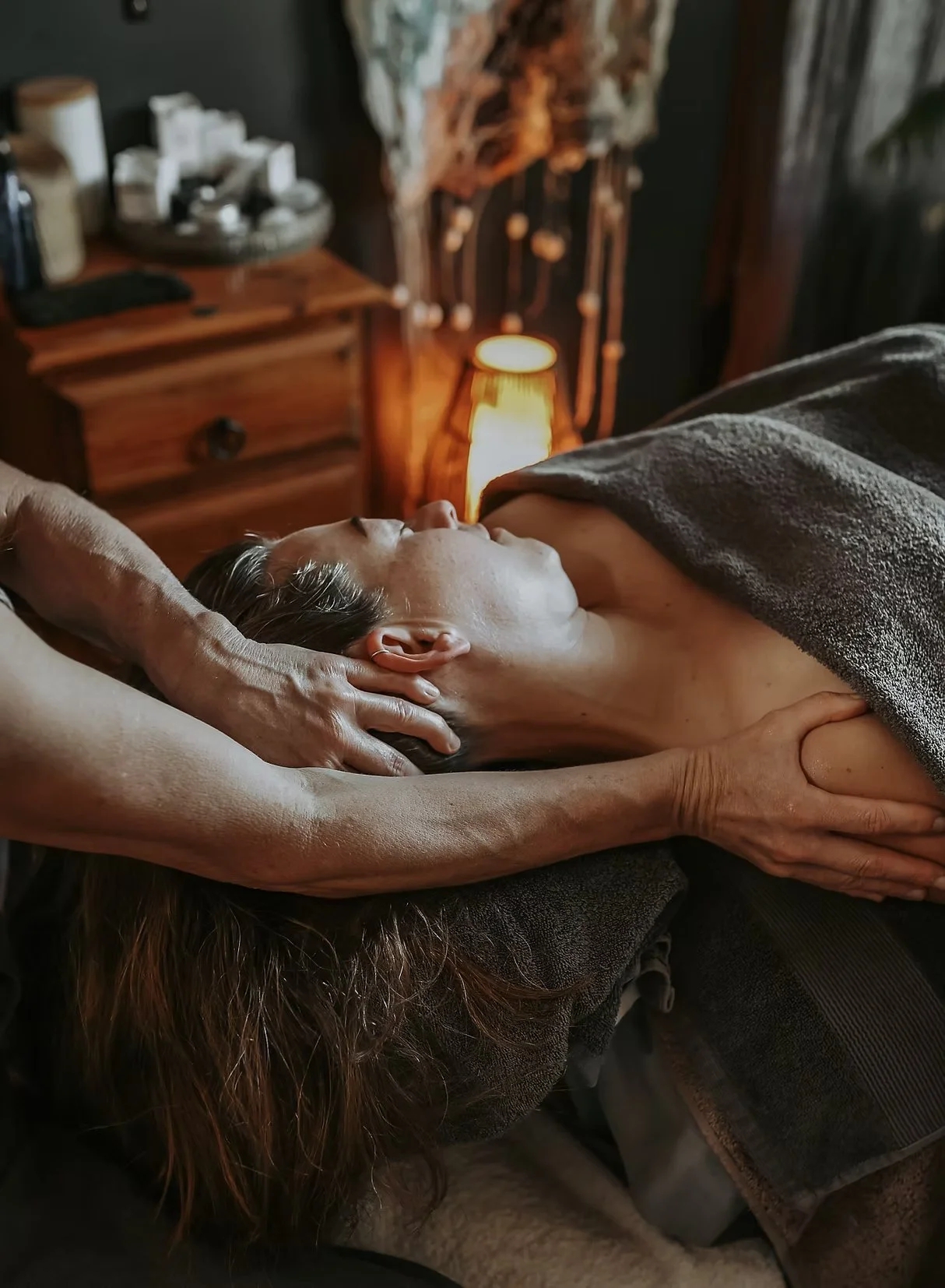 Gina is gently stretching the patients neck while they're laying down on the massage table.