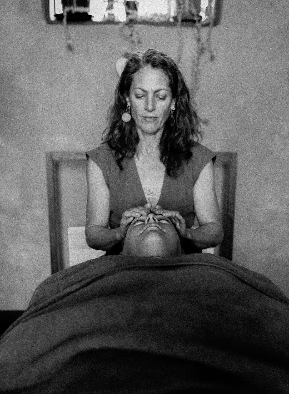 Gina is performing Cranioscral therapy on a patients forehead while they're relaxing on the massage table.