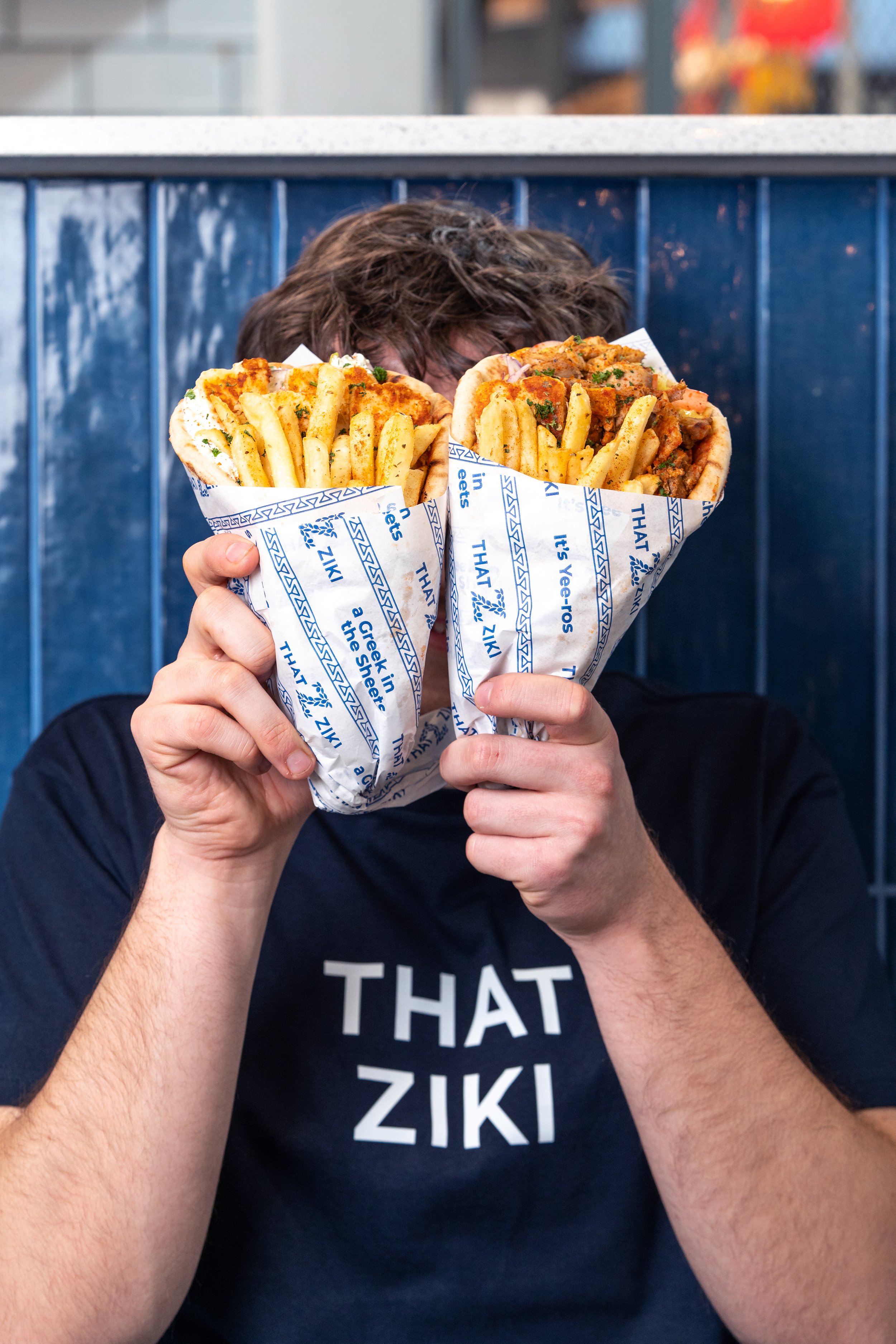 Fresh Thatziki Greek gyros wraps with fries being held by one of the founders.