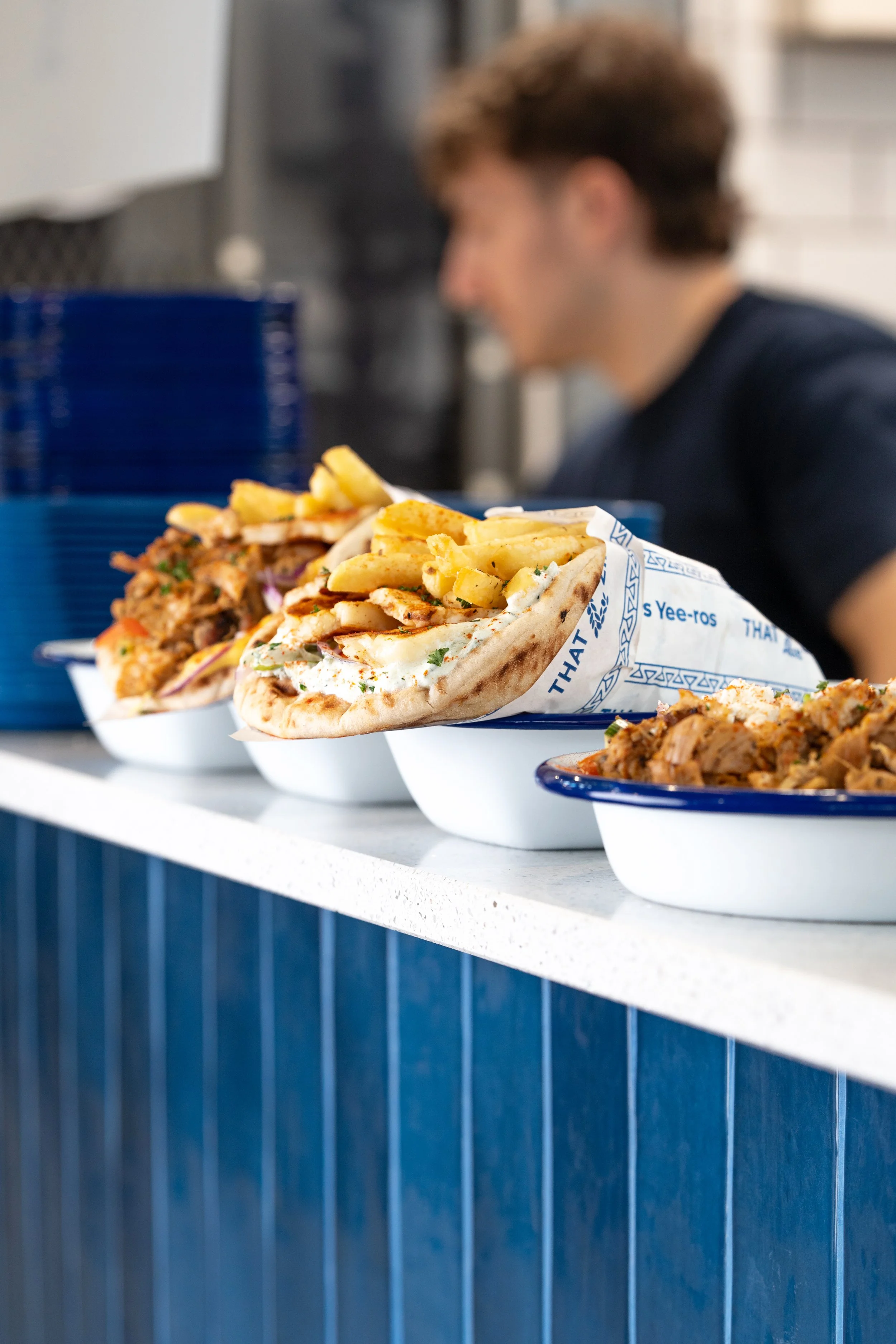 Close-up of an order leaving the Thatziki kitchen, 2 Gyros and a side of fries.