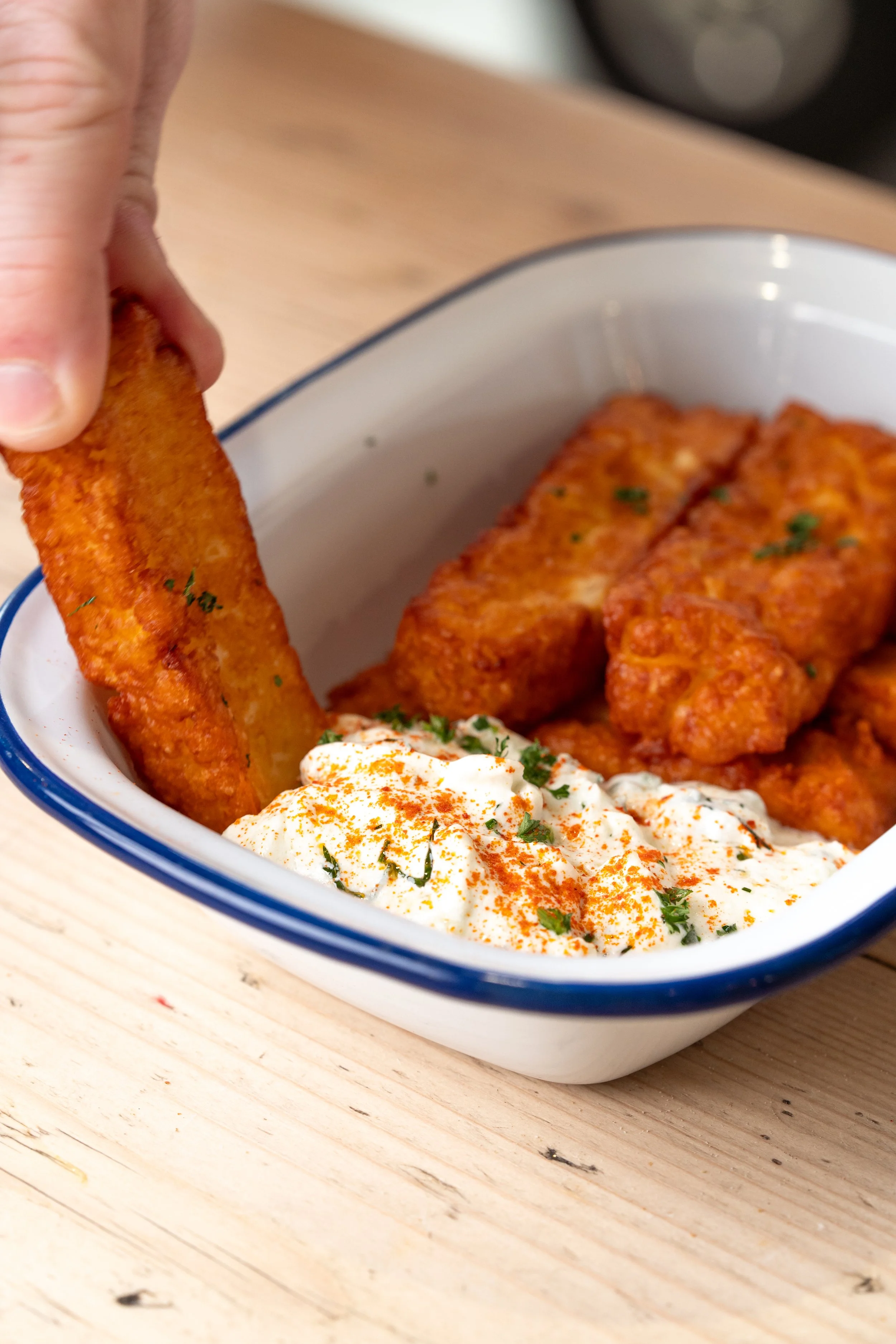 A portion of Golden Halloumi Fries being dipped into some thick Thatziki sauce