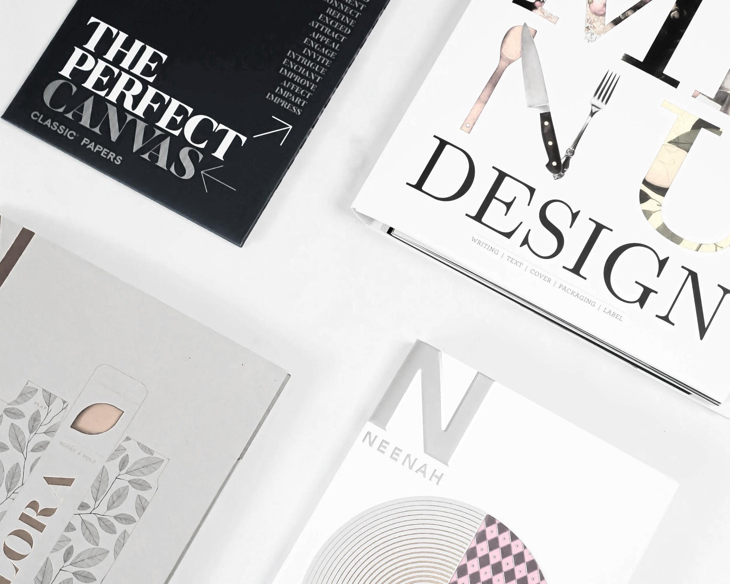 Collection of printed paper products, including magazines and catalogs, featuring text and graphic designs, with visible cutouts and page elements.