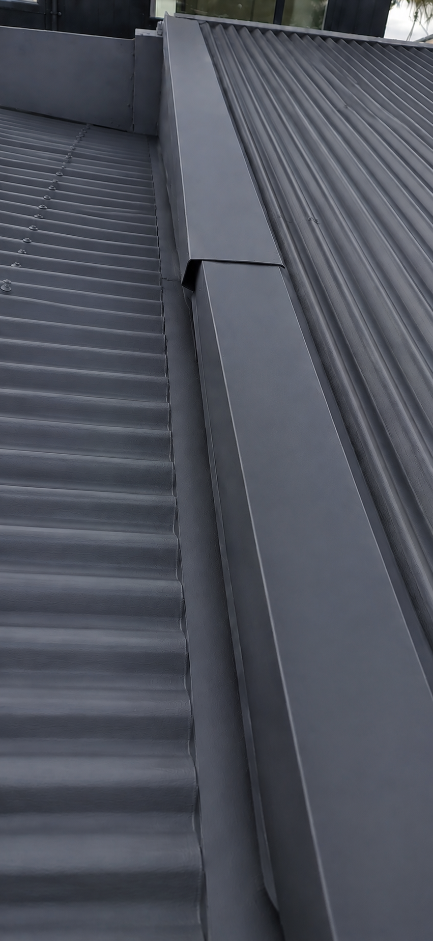 Charcoal finish coat applied during metal roof painting in Auckland