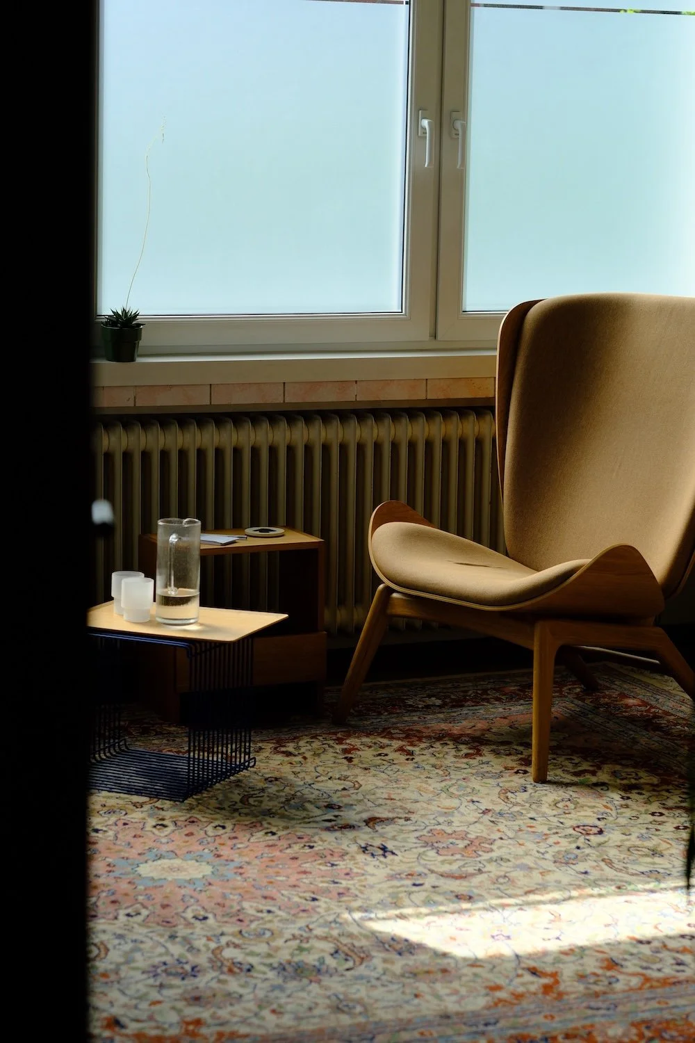 Gemütlicher Warteraum der Praxis mit Sessel, Fenster und Pflanzen