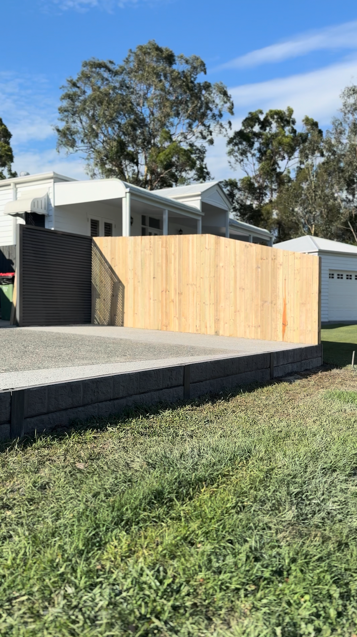 Concrete sleeper wall with concreted driveway extension and timber fencing completed in Coomera