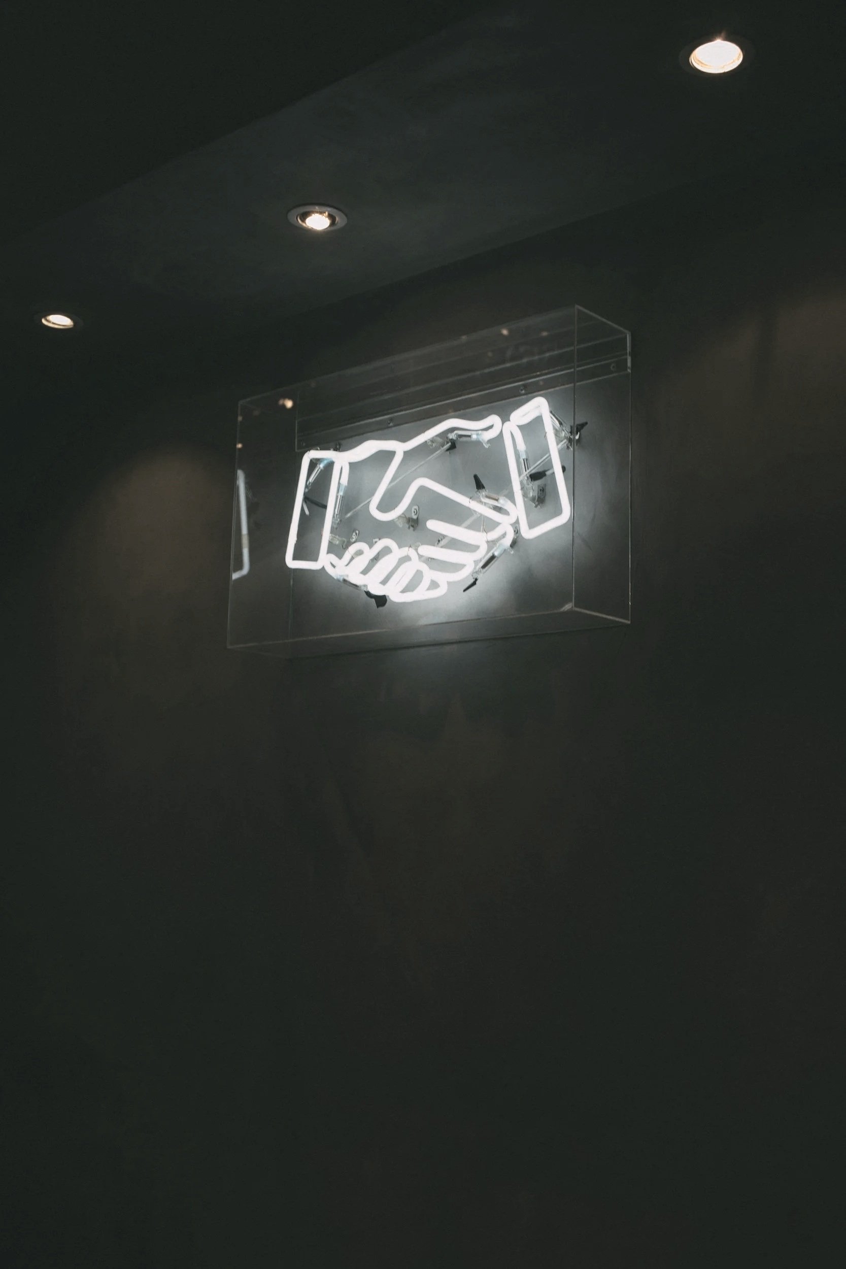 Neon sign of a handshake, implying collaboration.