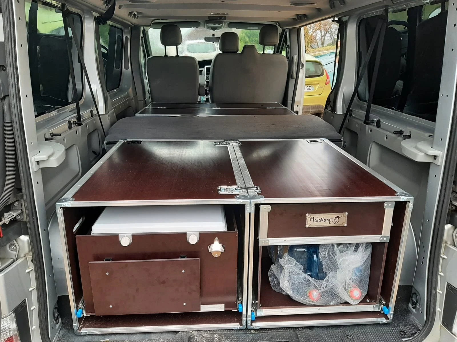 Véhicule transformé en camping-car, avec un espace de rangement et un plan de travail en bois.