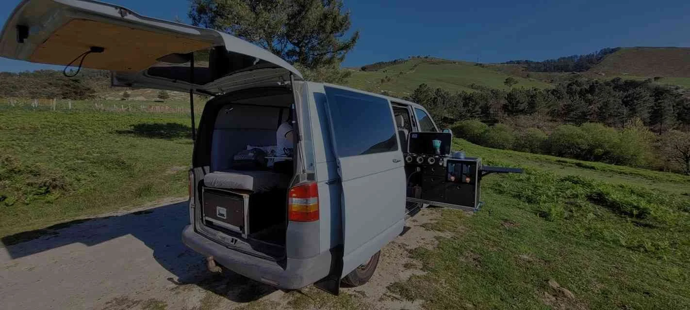Un fourgon aménagé en camping-car avec une cuisine extérieure.