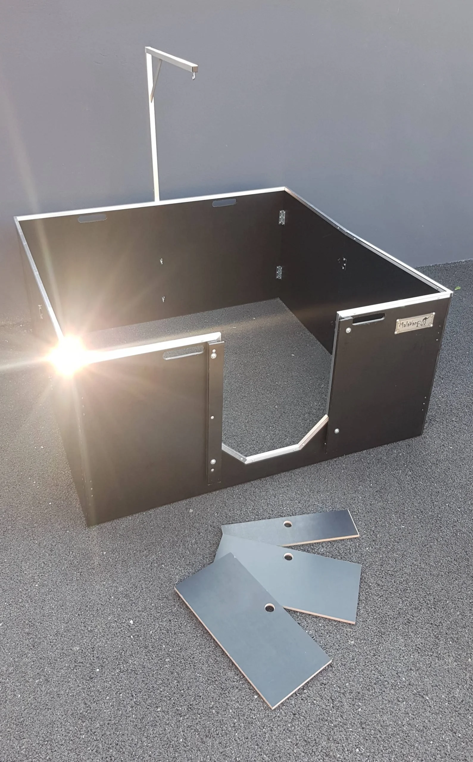 Une structure en métal avec plusieurs panneaux noirs, certains étant détachés à côté. La structure semble être en cours d'assemblage ou de réparation.