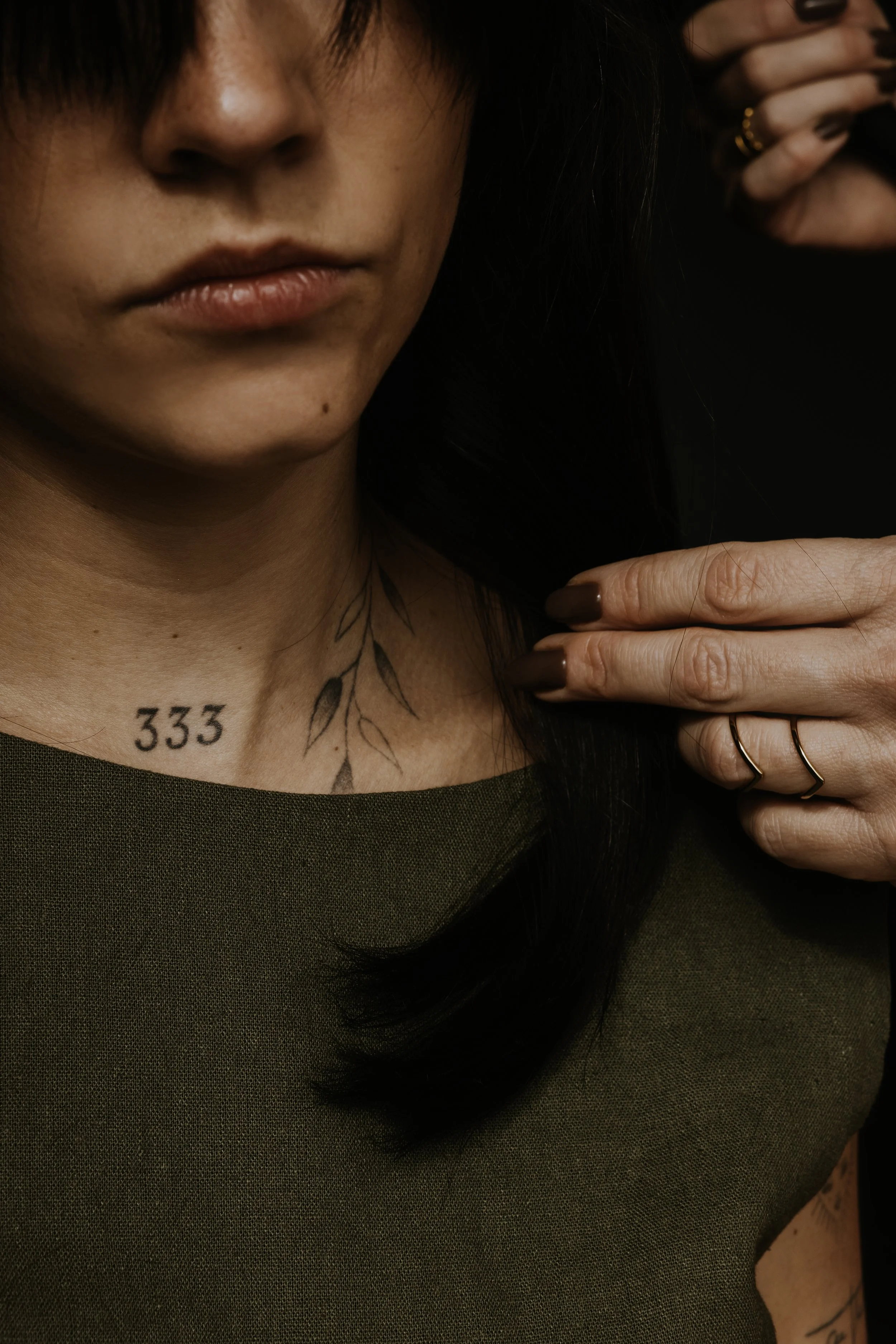 Close-up van een vrouw met donkere haar en tatoeages, het haar wordt gestyled door een kapster LONN.