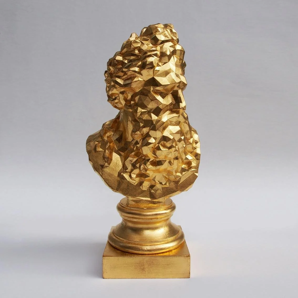Gold-colored abstract sculpture of a person's bust on a square base
