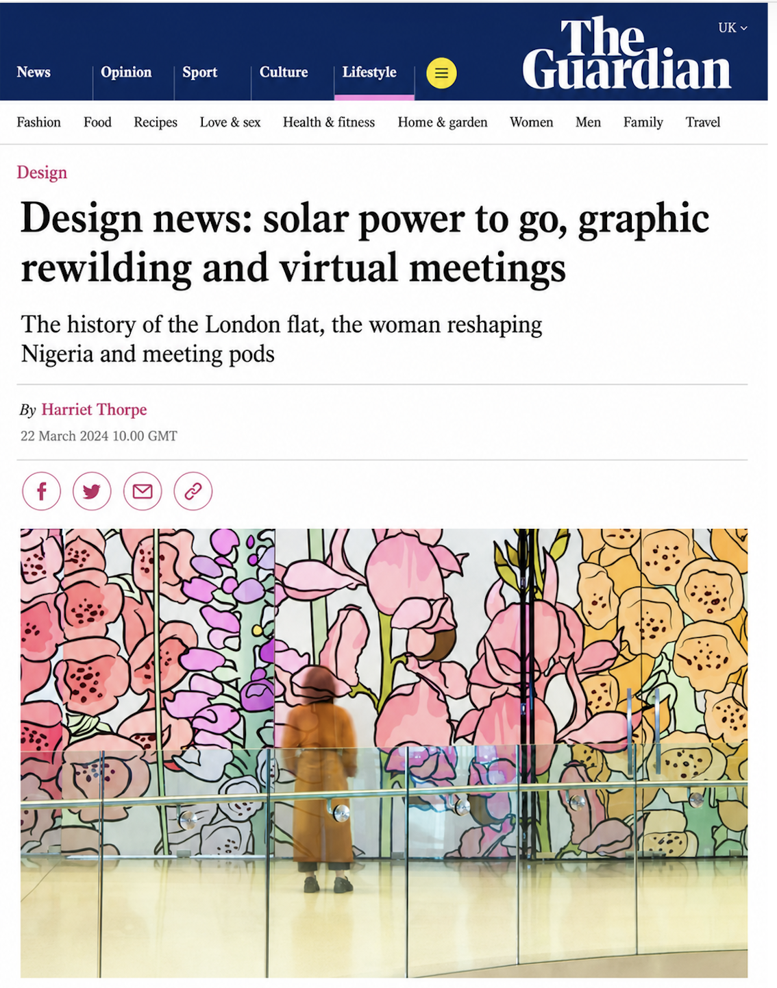 A large digital article headline from The Guardian website on a screen with a colorful floral background behind glass. The headline reads about solar power, graphic rewilding, and virtual meetings, with a smaller subheading and author name below.