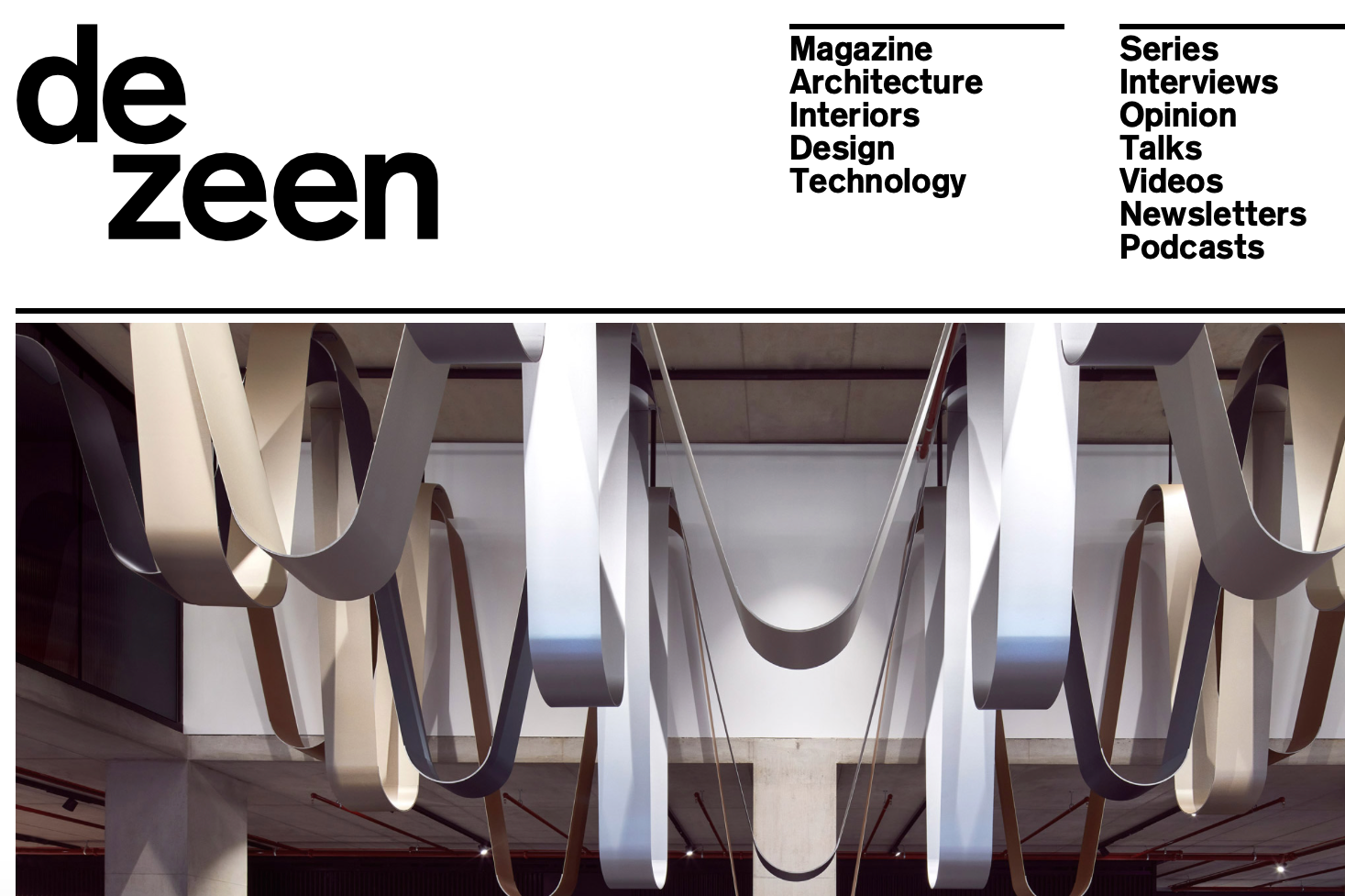 Cover of de zeen magazine featuring modern architectural installation with large, looping, ribbon-like metal sculptures hanging from the ceiling.