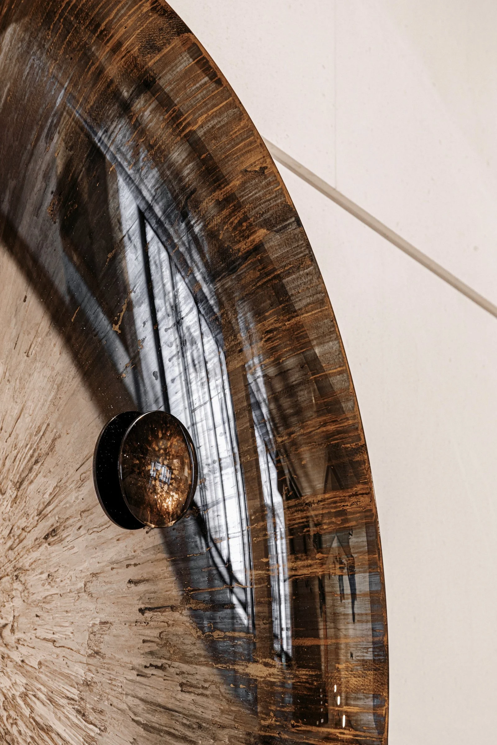 Close-up of a curved wooden speaker with a black grille and a white ceiling in the background.